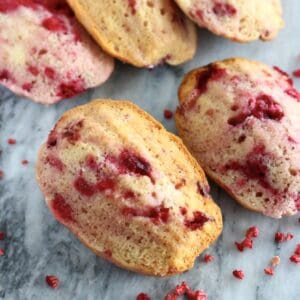 Five gluten-free vegan raspberry madeleines on a marble background