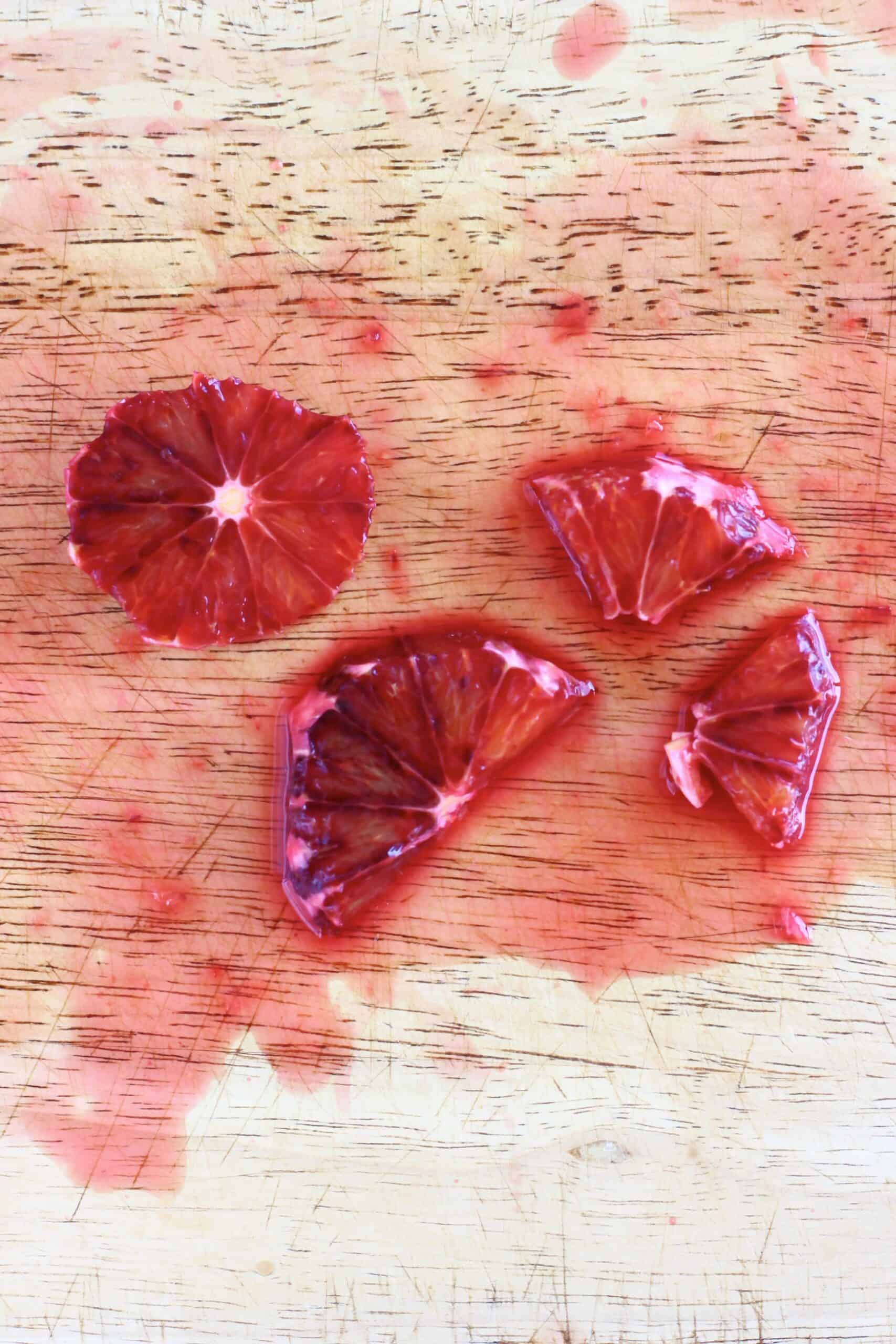Blood orange slices cut into halves and quarters on a chopping board