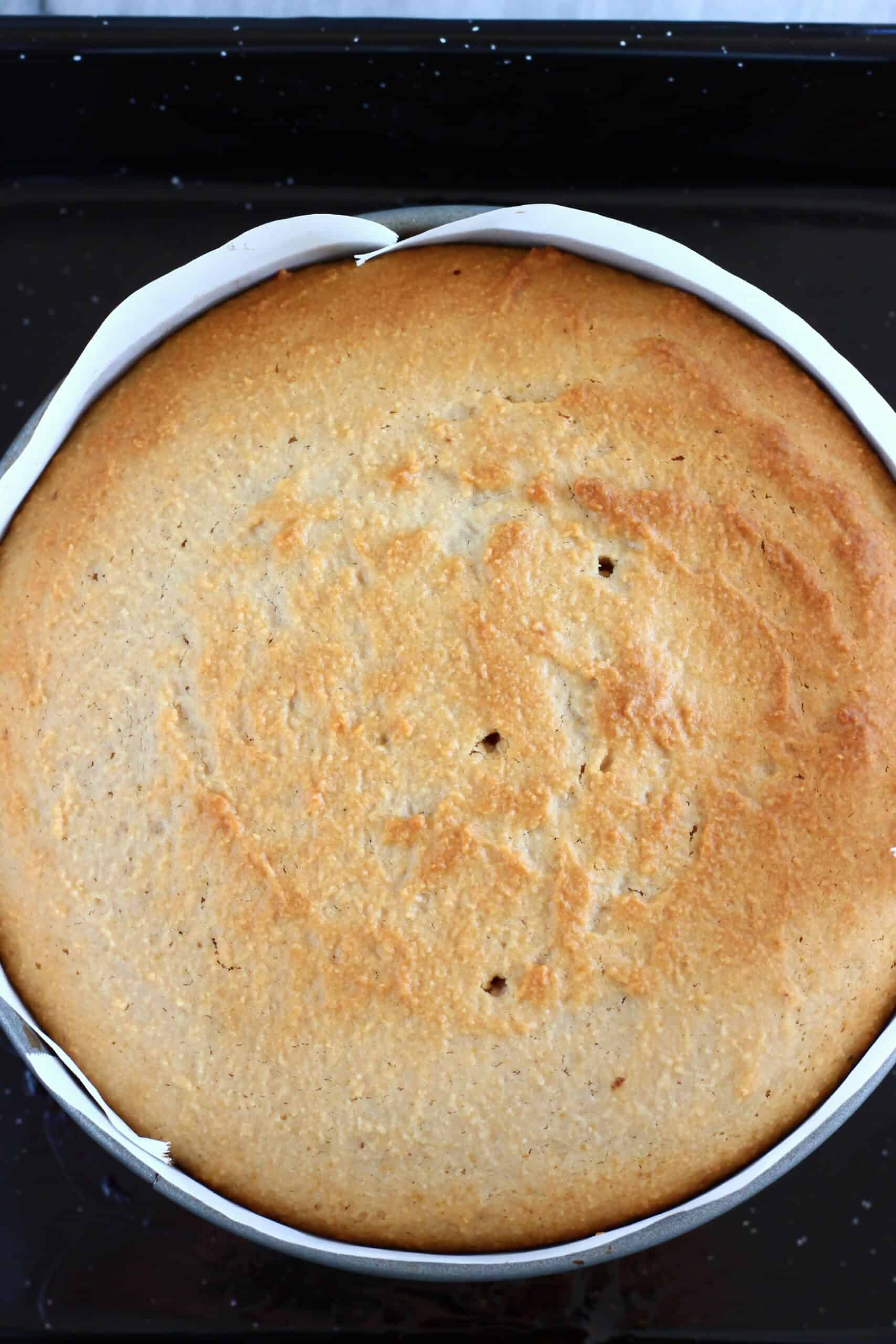 A baked gluten-free vegan blood orange cake in a round springform baking tin lined with baking paper