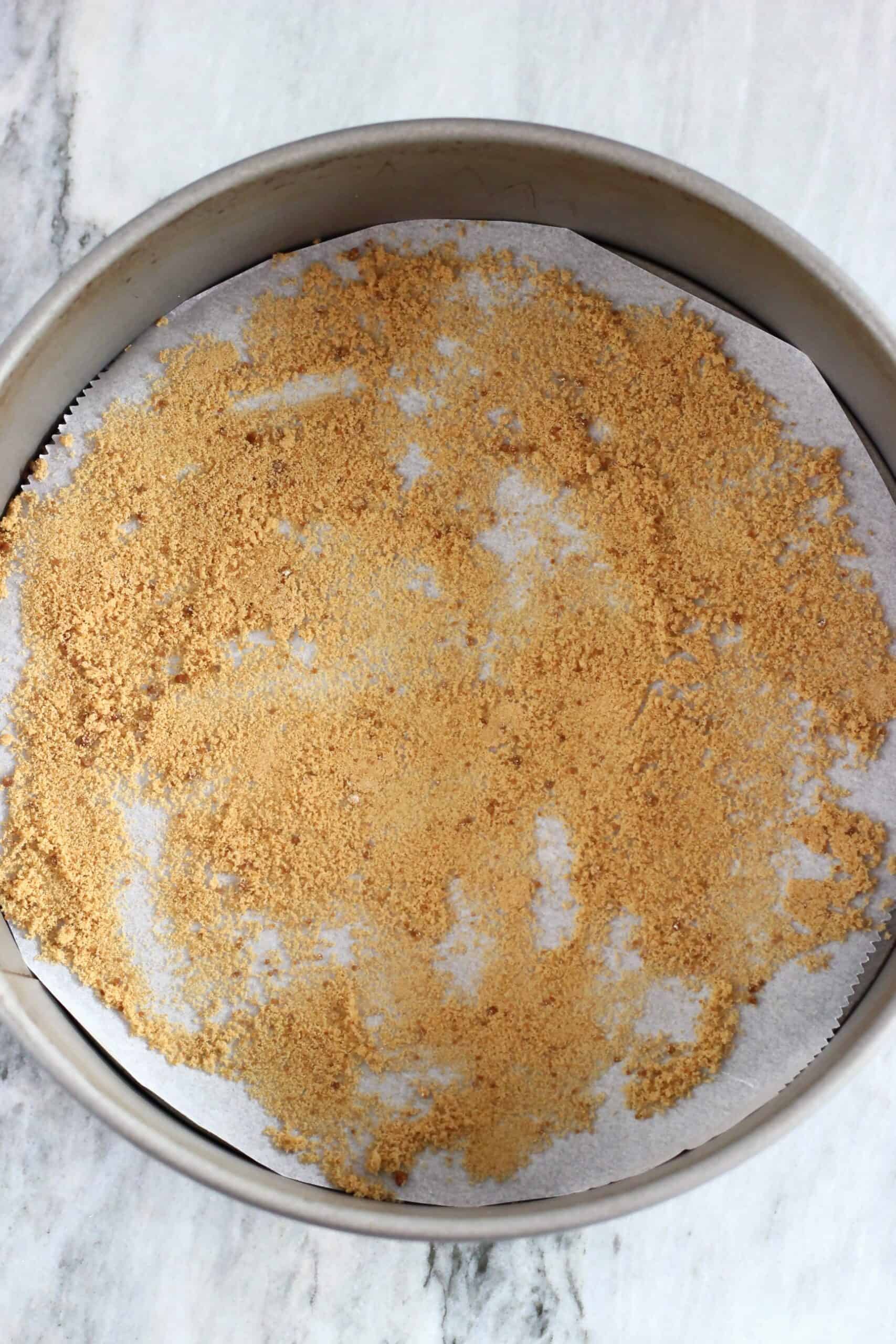 A round springform baking tin lined with baking paper sprinkled with coconut sugar