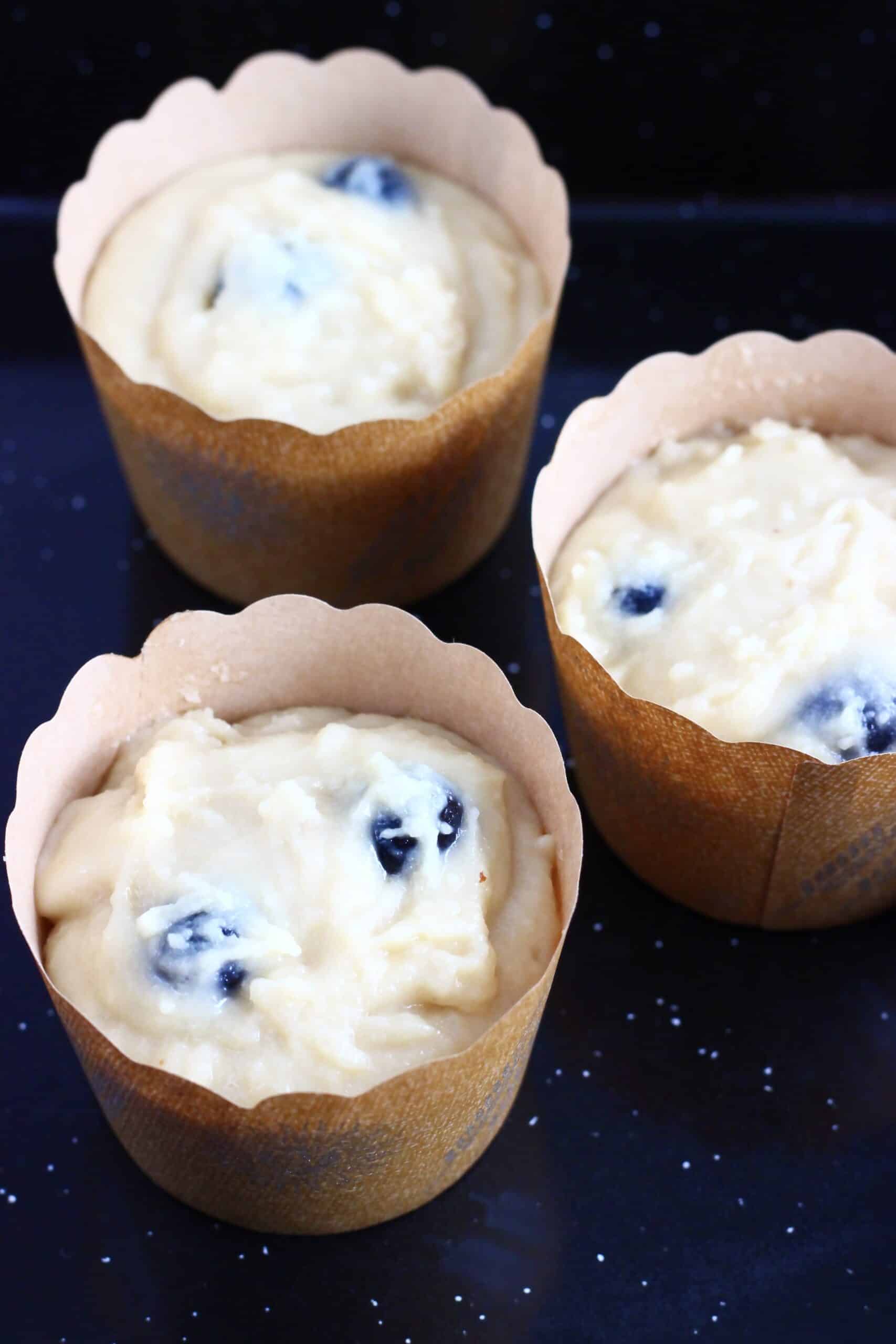 Raw gluten-free vegan lemon blueberry muffin batter in muffin cases in a muffin tin