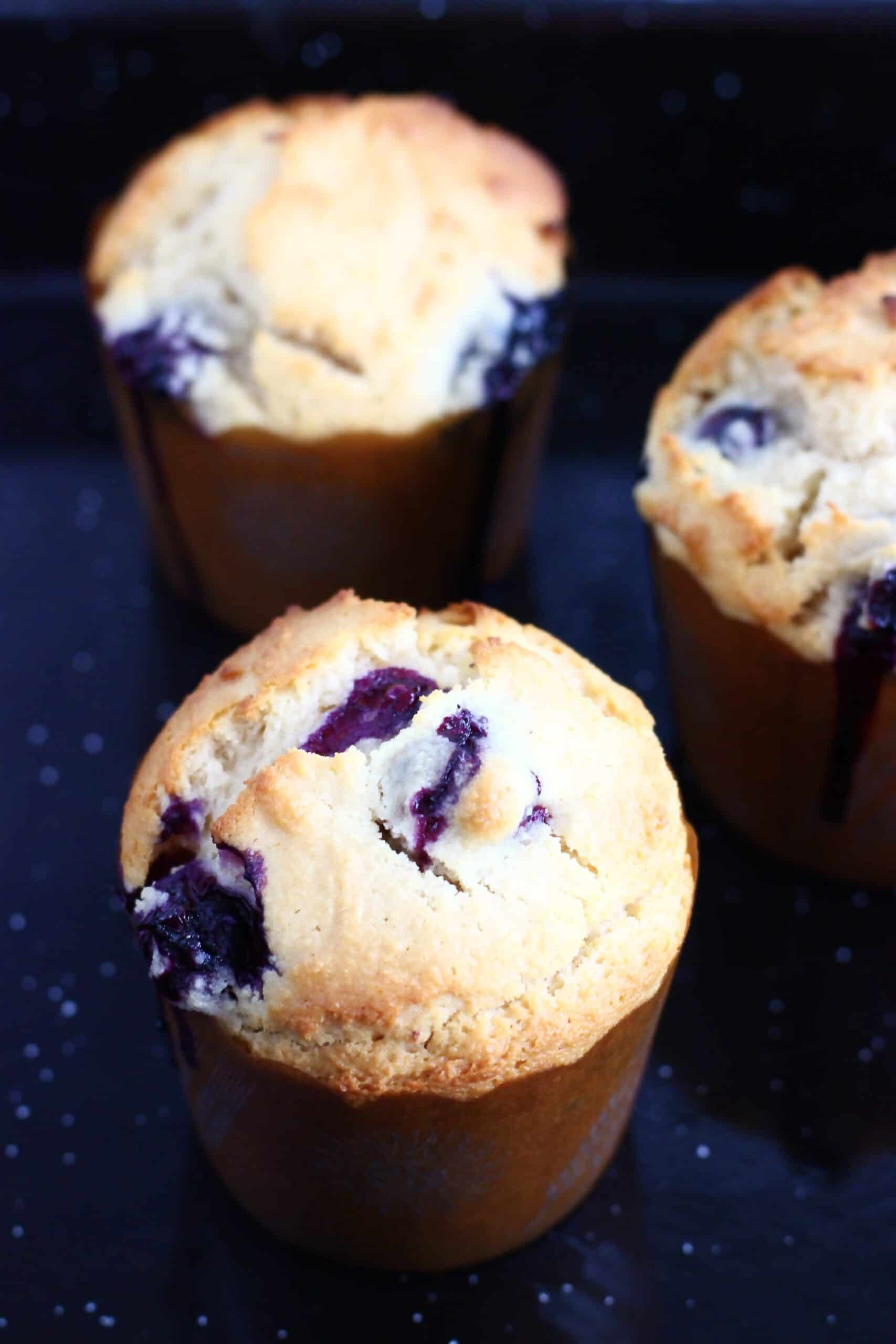 Baked gluten-free vegan lemon blueberry muffins in muffin cases in a muffin tin