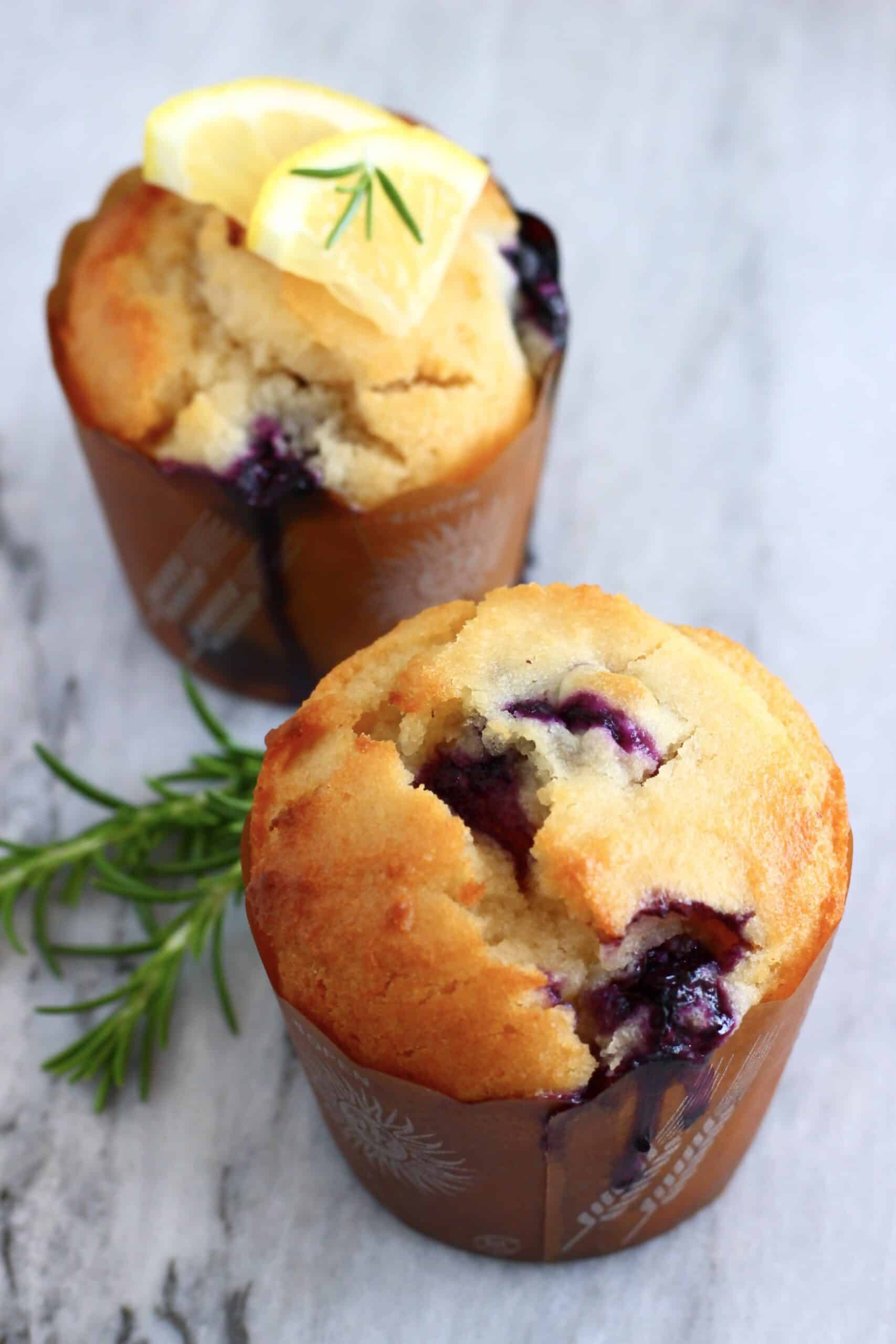 Two gluten-free vegan lemon blueberry muffins on a marble background