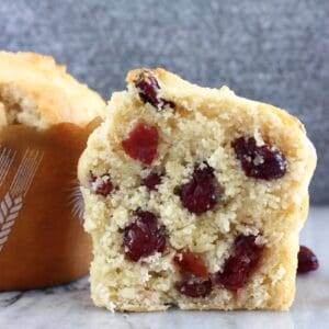 A halved gluten-free vegan cranberry muffin on a marble background