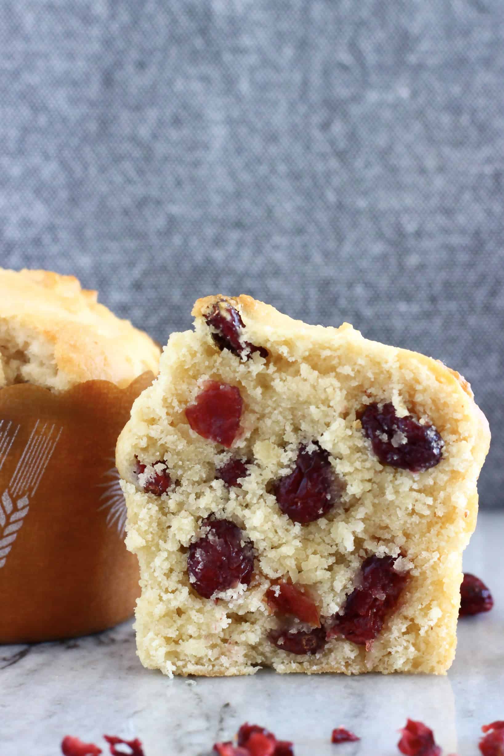 A halved gluten-free vegan cranberry muffin on a marble background