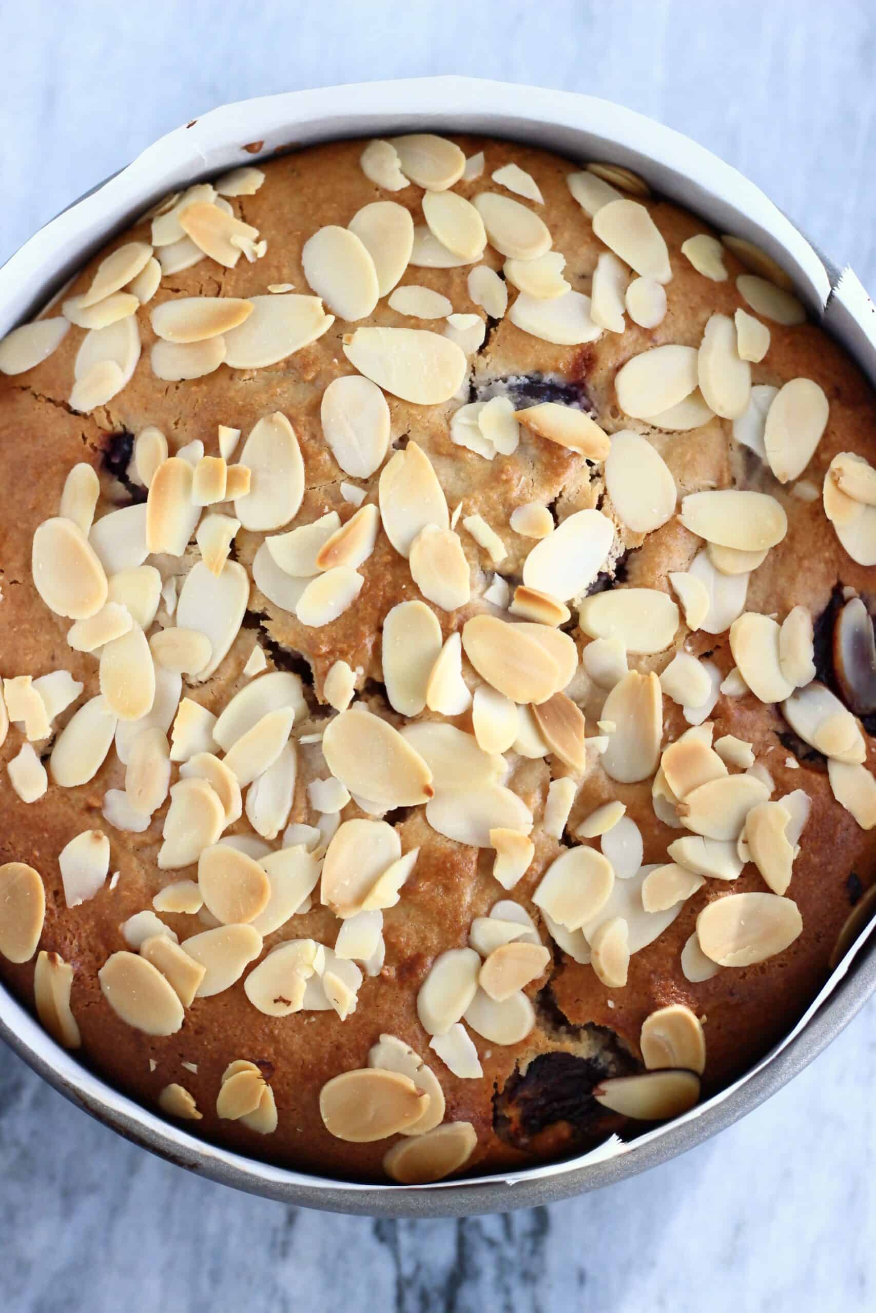 A baked gluten-free vegan cherry cake in a round springform baking tin lined with baking paper