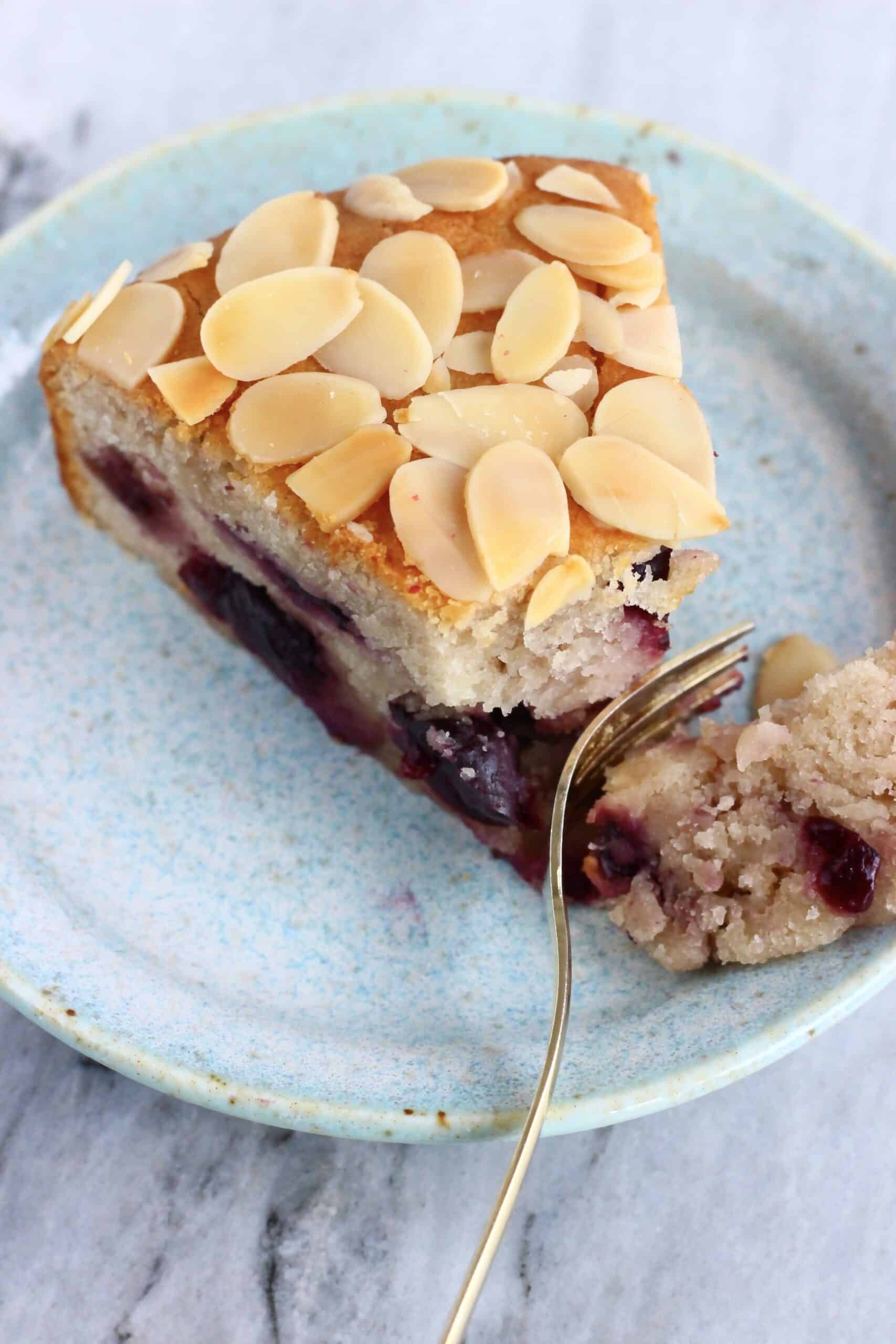 A slice of gluten-free vegan cherry cake with a fork taking a mouthful