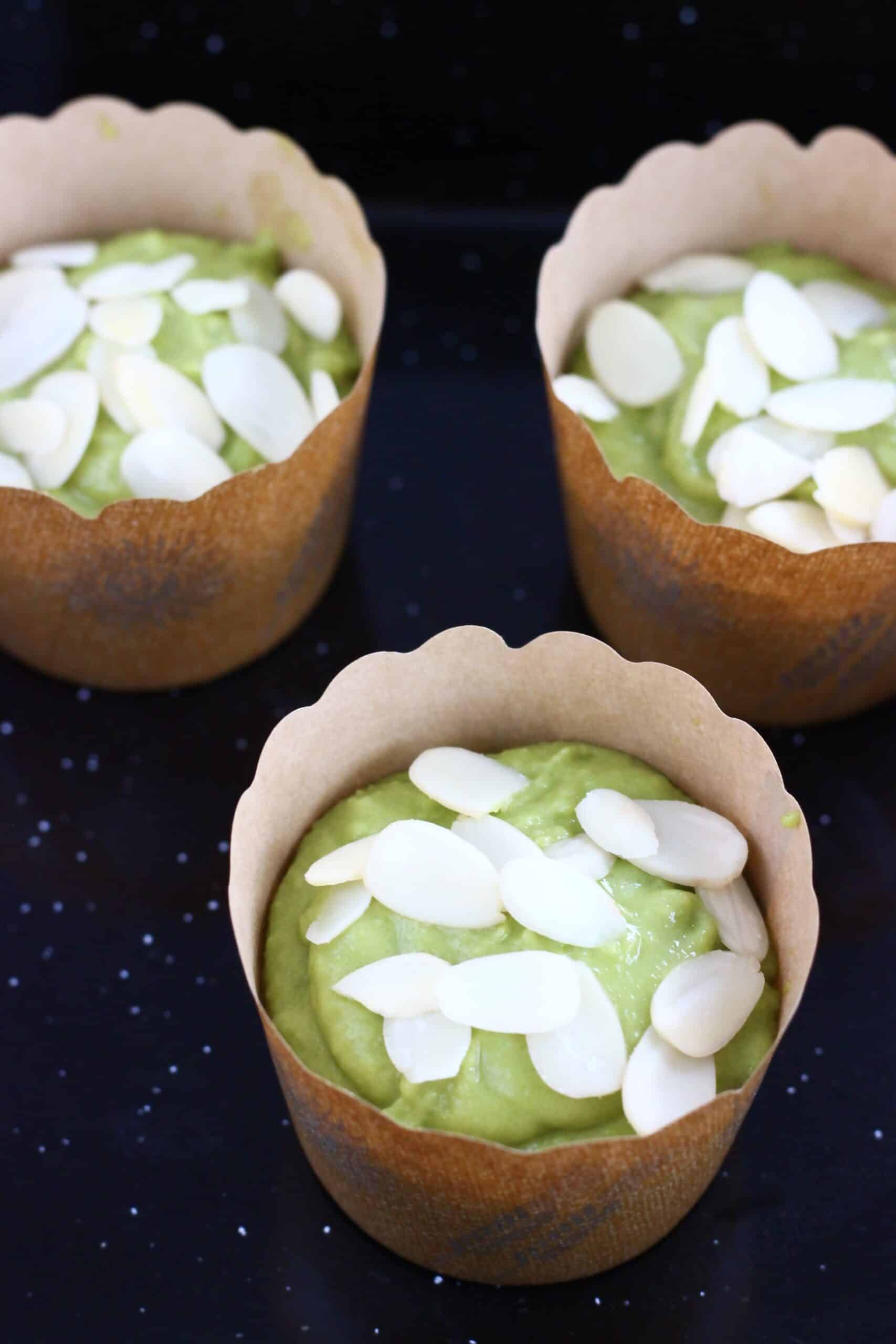 Raw gluten-free vegan matcha muffins batter in muffin cases topped with flaked almonds