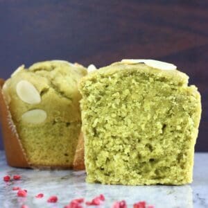 A halved gluten-free vegan matcha muffin with a whole muffin next to it on a marble background