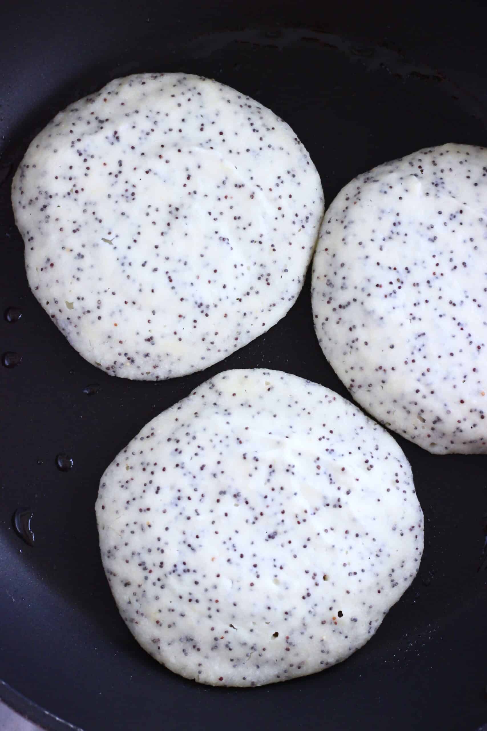 Raw gluten-free vegan lemon poppy seed pancakes being cooked in a frying pan