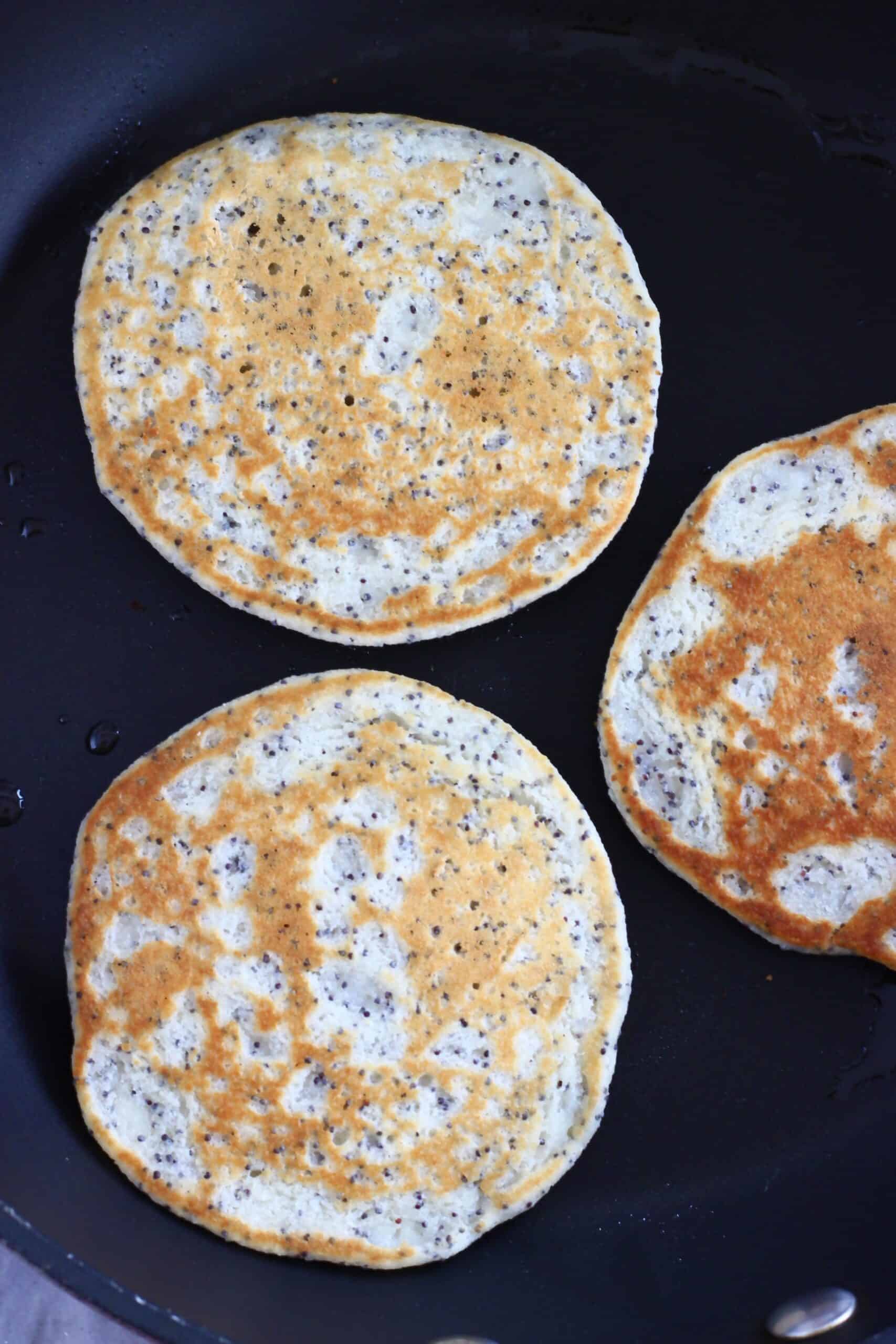 Gluten-free vegan lemon poppy seed pancakes being cooked in a frying pan