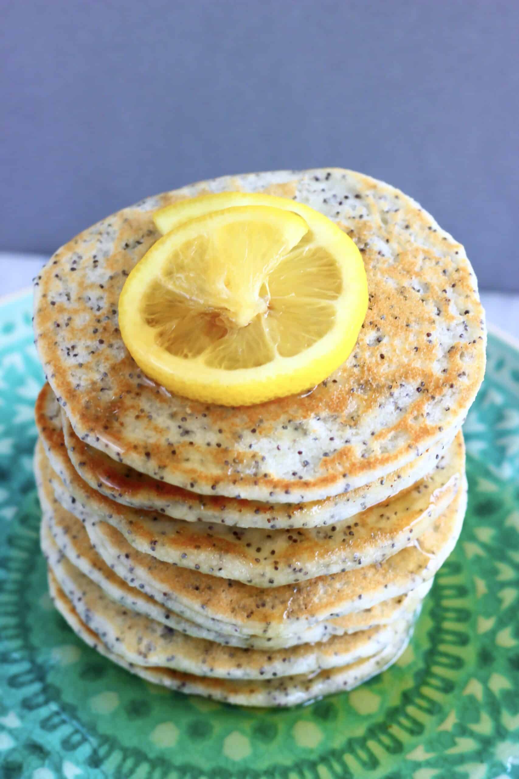 A stack of gluten-free vegan lemon poppy seed pancakes on a plate with syrup