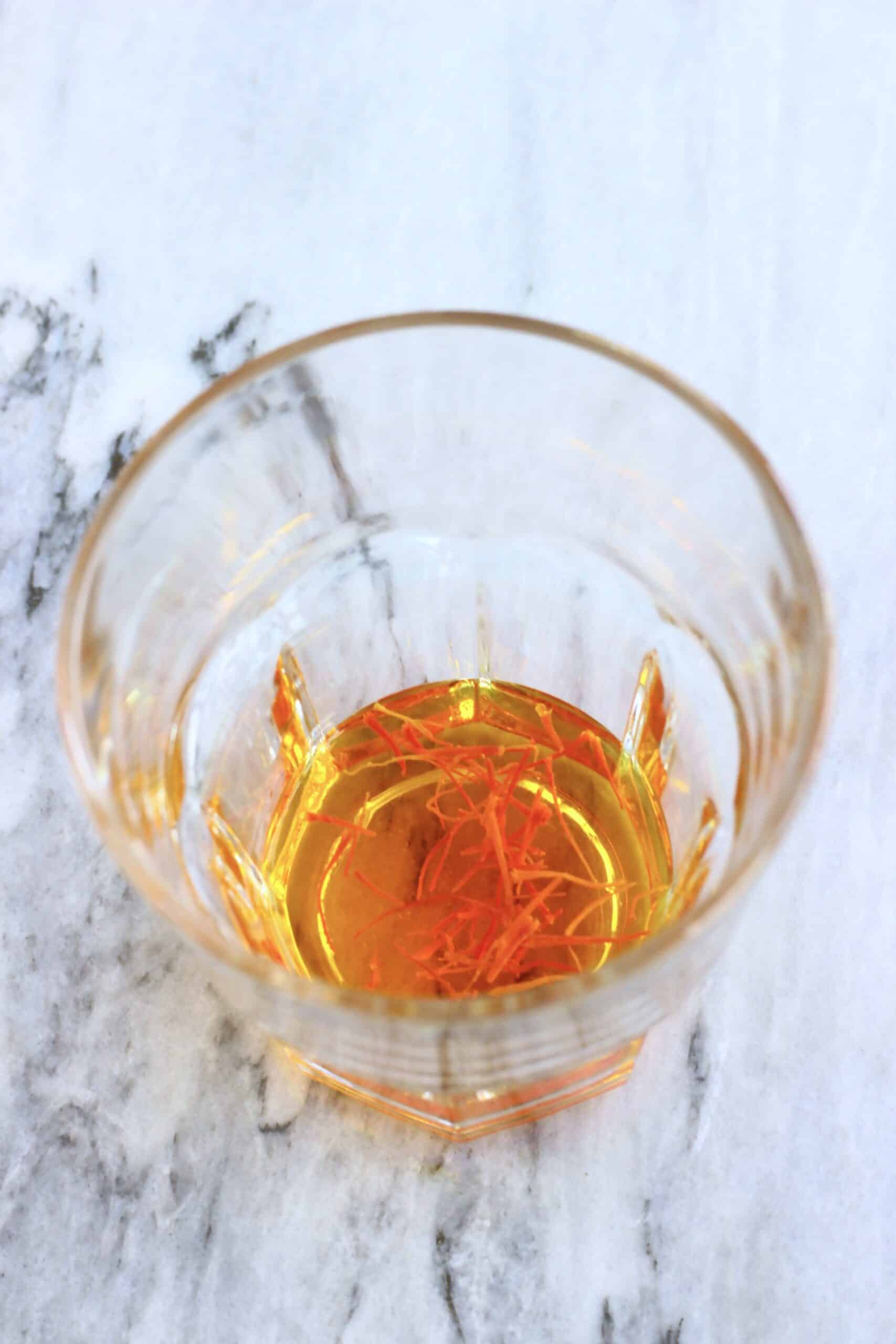 Saffron strands being soaked in hot water in a glass