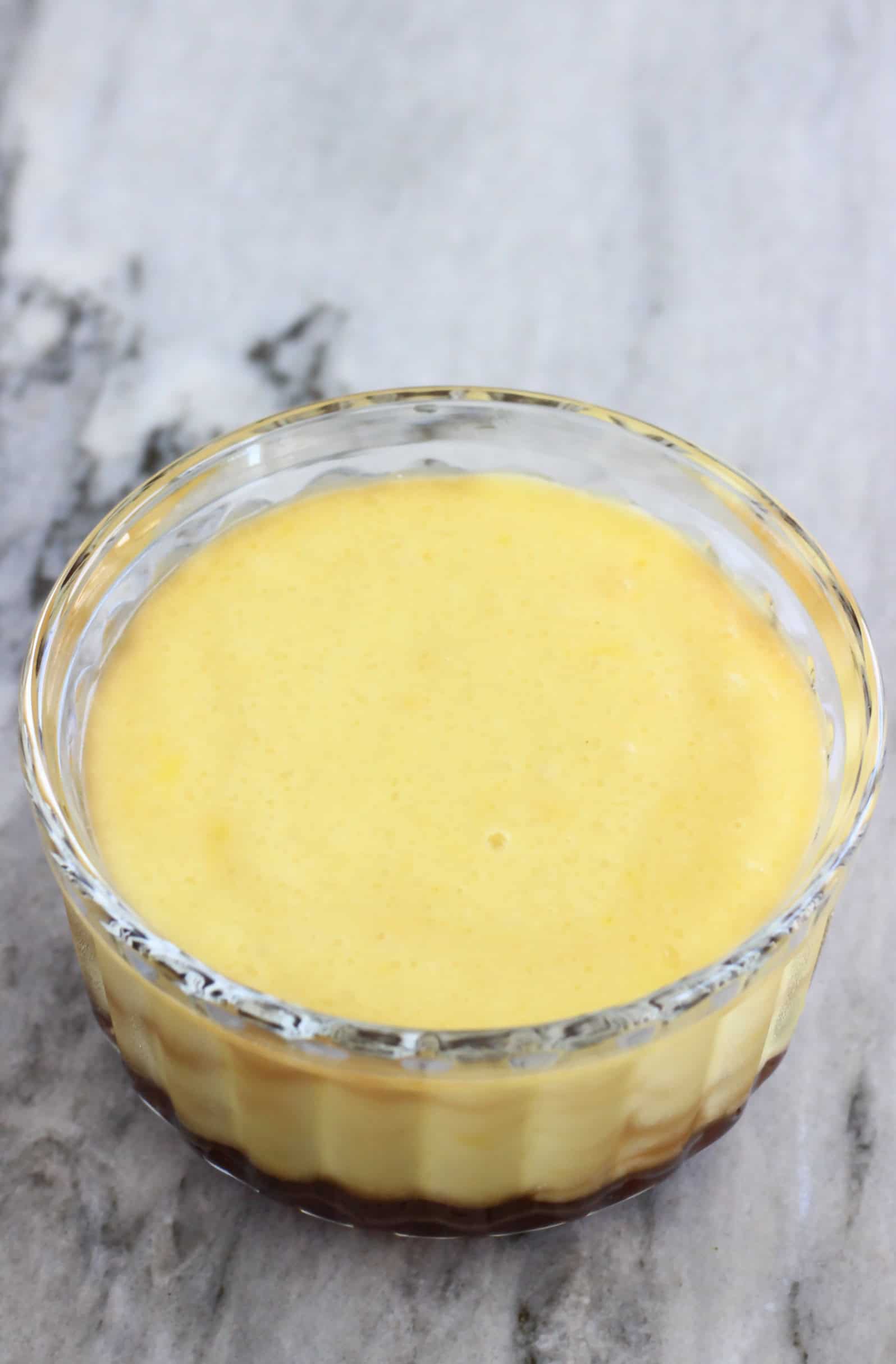 A vegan crème caramel with brown syrup in a glass pot