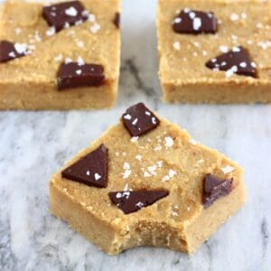 Three chickpea blondies with chocolate chunks with a mouthful taken out of one