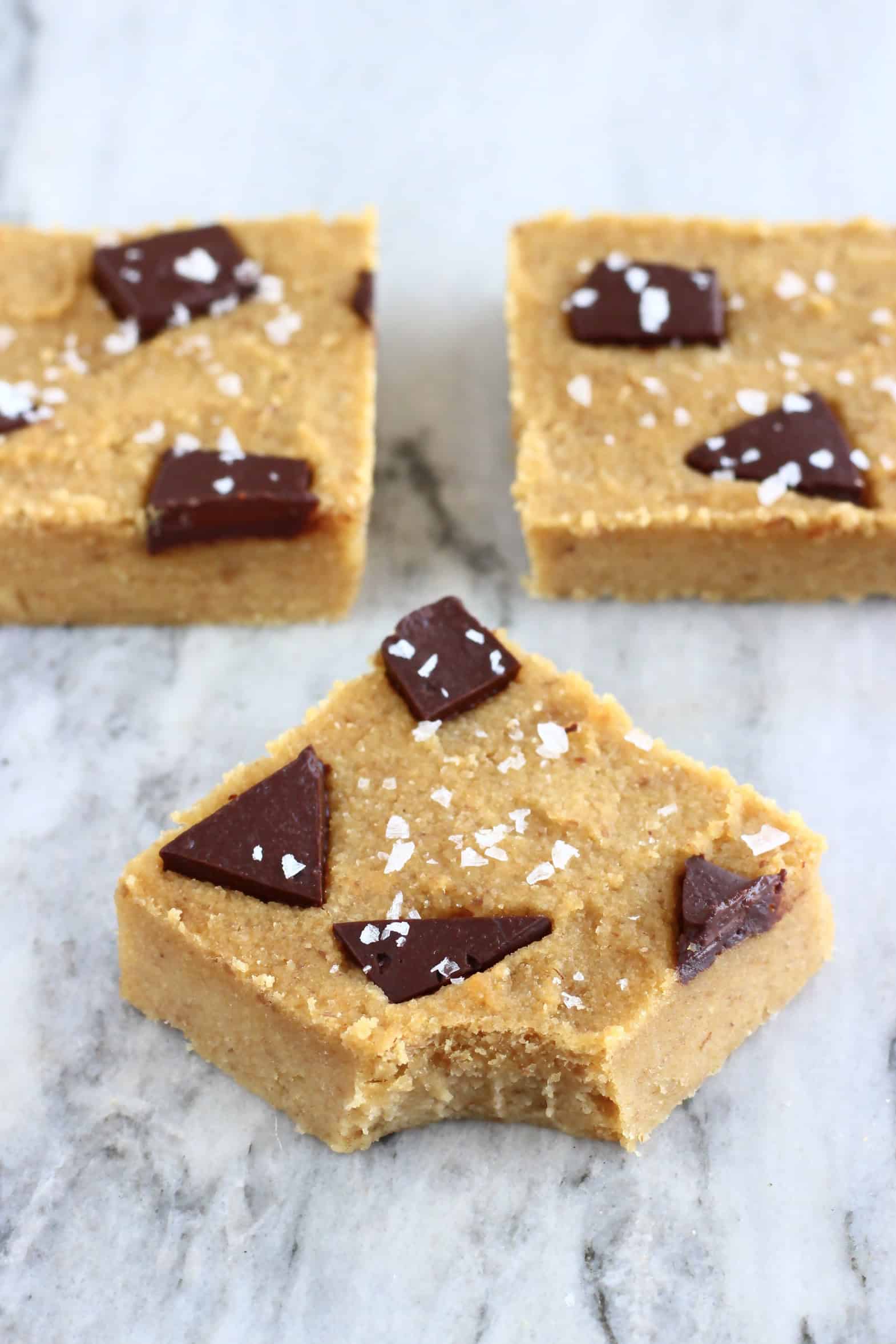 Three chickpea blondies with chocolate chunks with a mouthful taken out of one