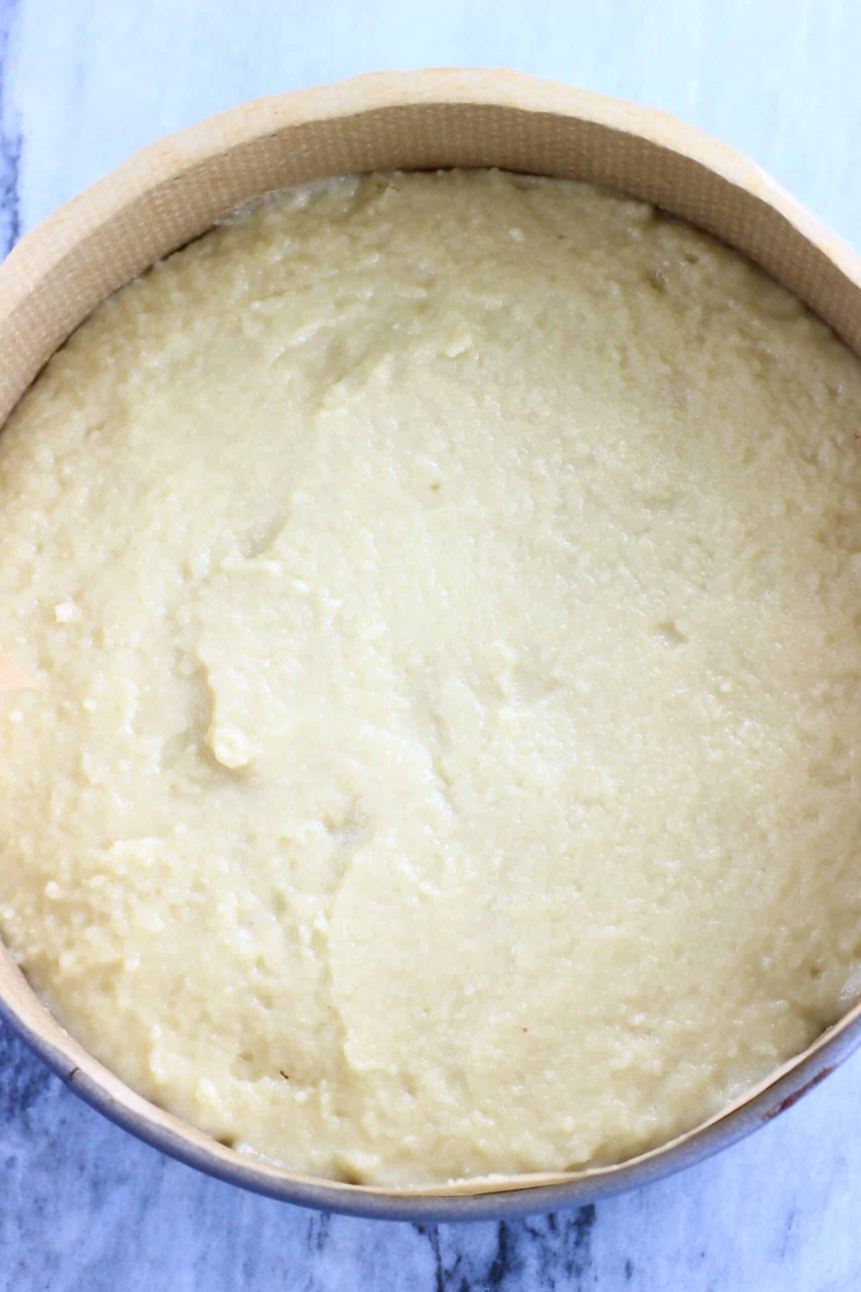 Raw gluten-free vegan lemon olive oil cake batter in a round springform baking tin lined with baking paper