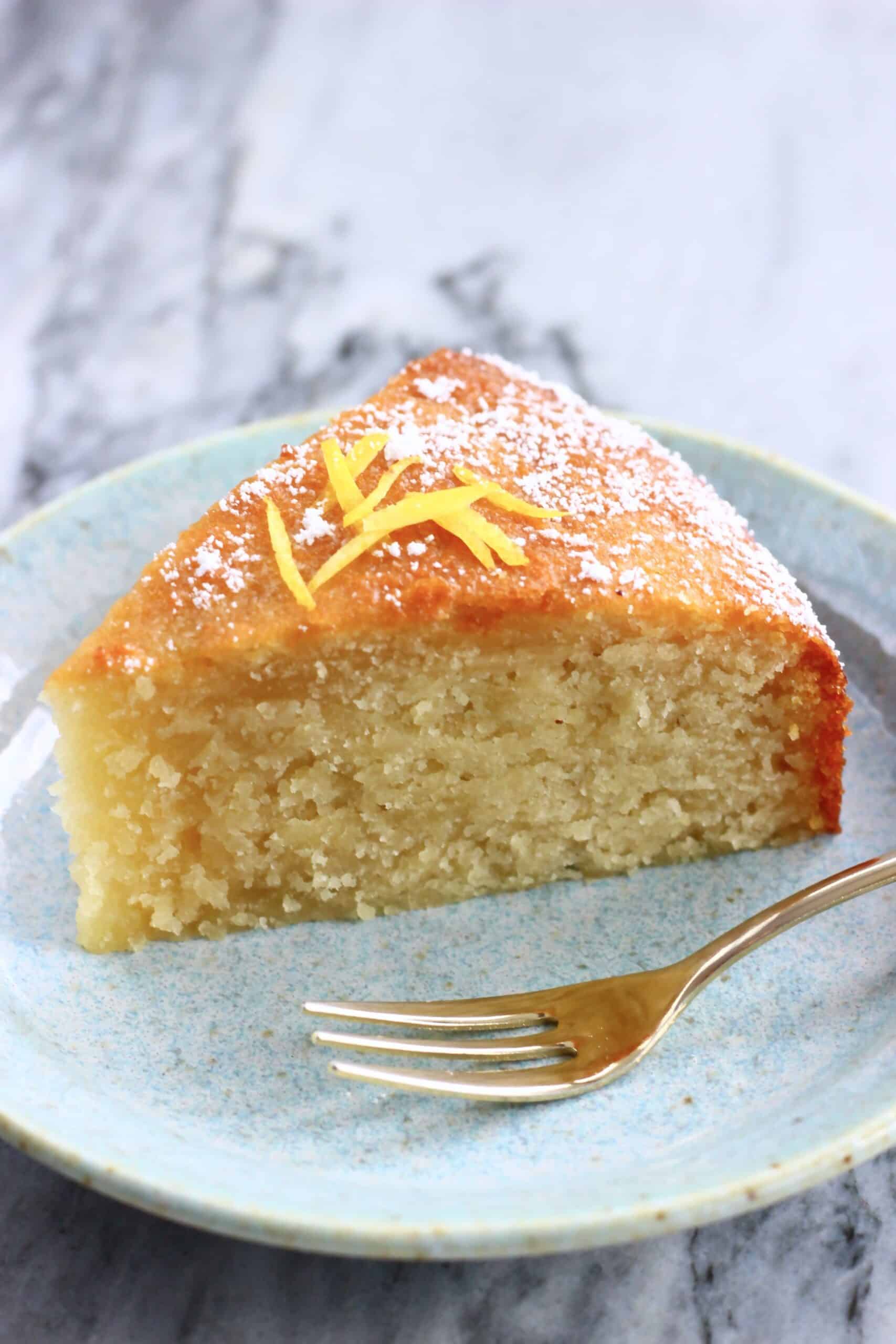 A slice of gluten-free vegan lemon olive oil cake on a plate with a fork