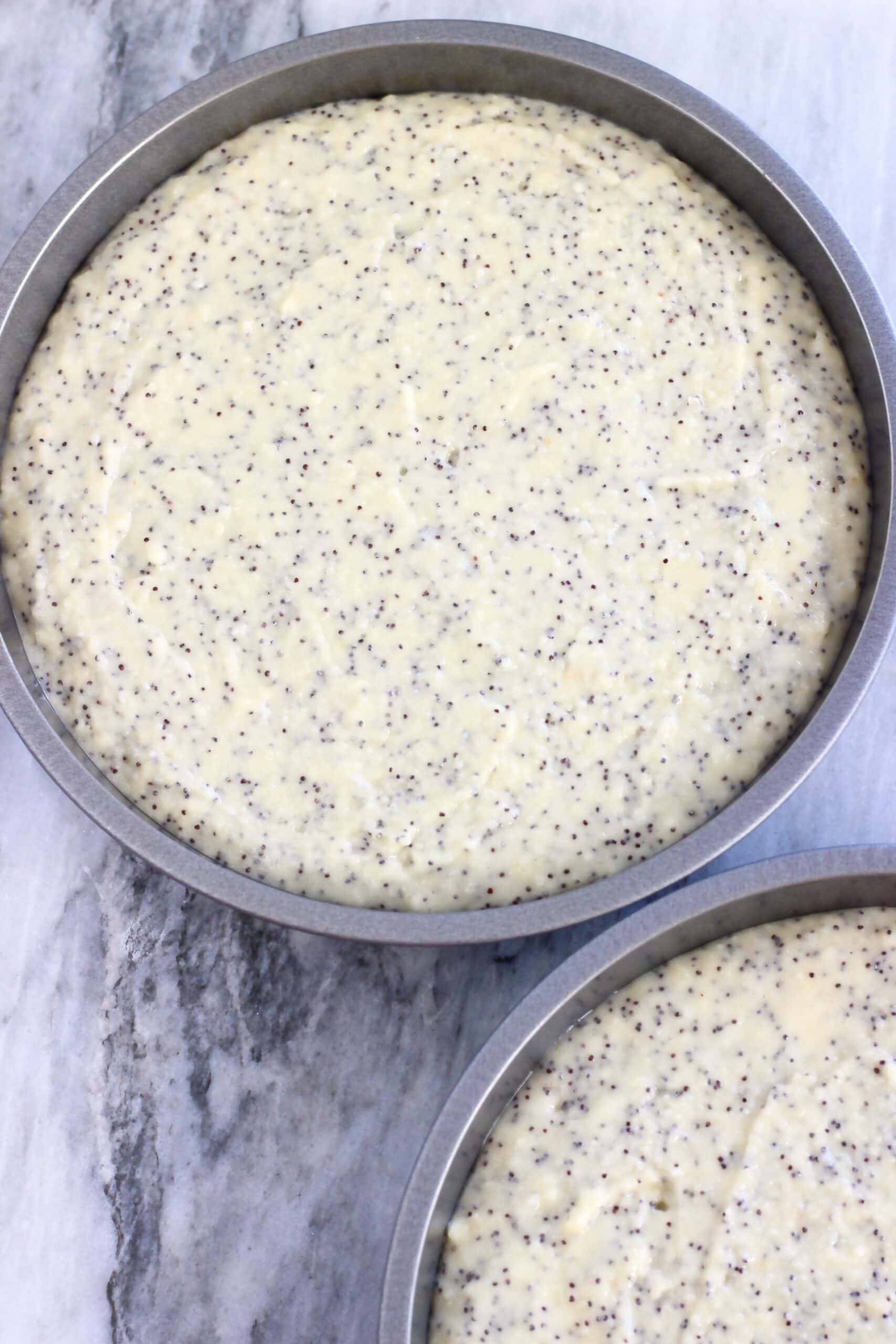 Raw vegan lemon poppy seed layer cake batter in two round baking tins