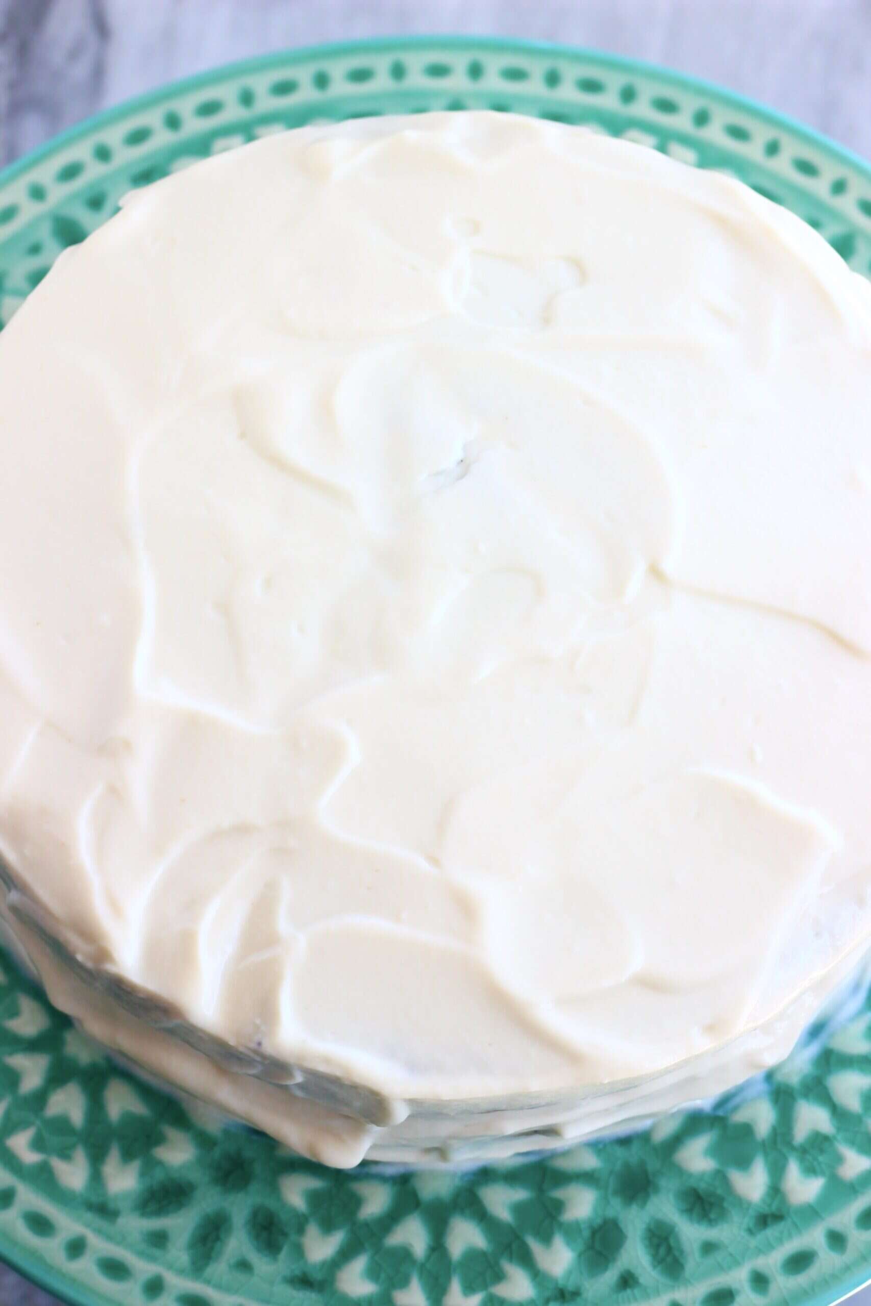 Vegan lemon poppy seed layer cake on a cake stand covered in frosting