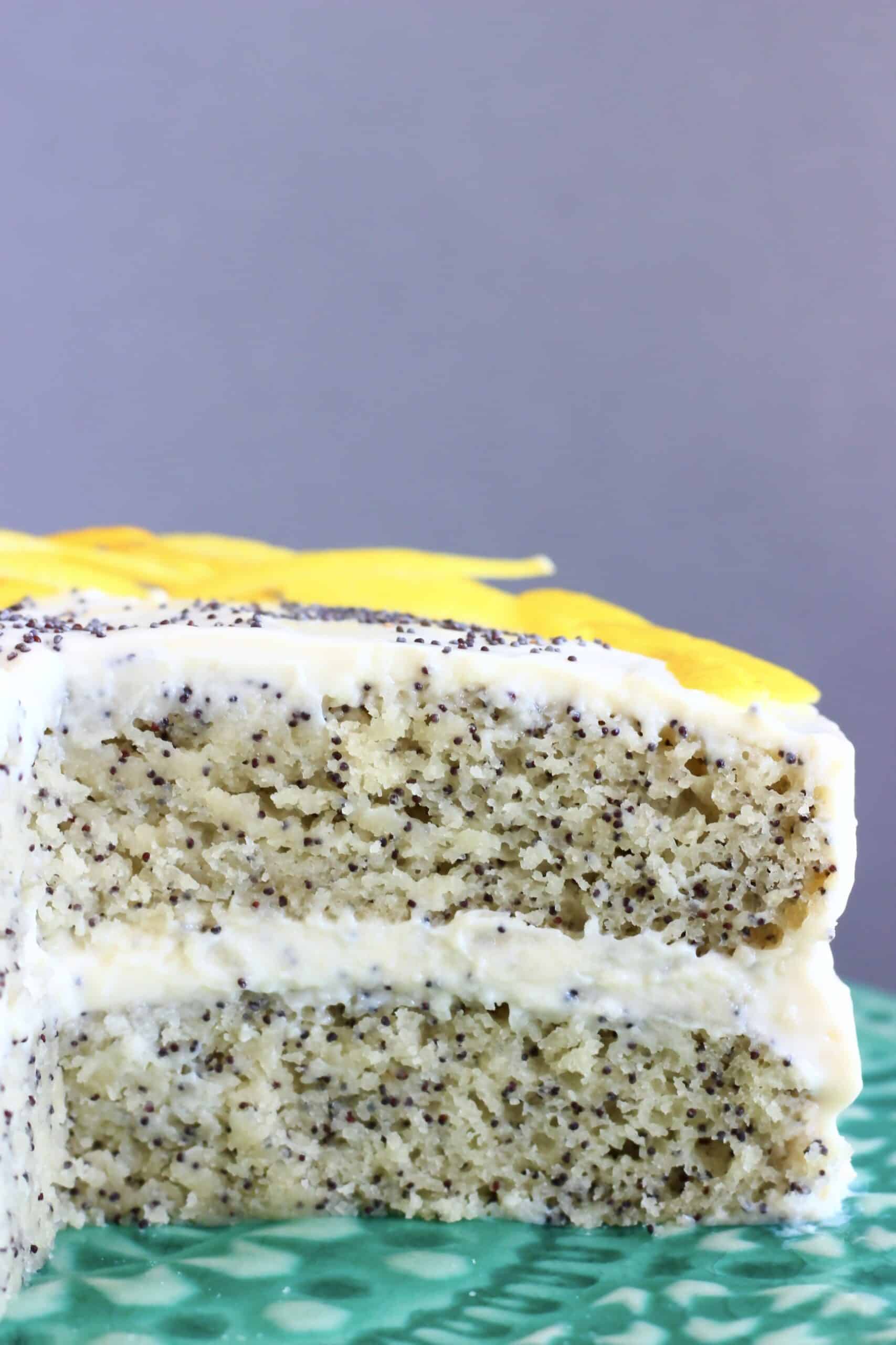 A sliced vegan lemon poppy seed layer cake on a cake stand