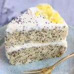 A slice of vegan lemon poppy seed layer cake on a plate with a fork