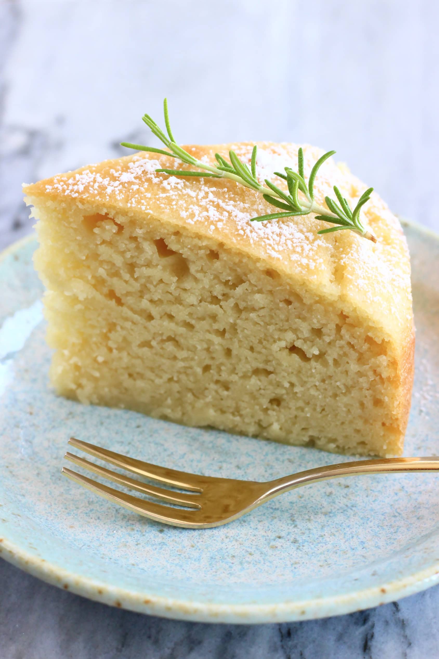 A slice of vegan olive oil yogurt cake on a plate with a fork
