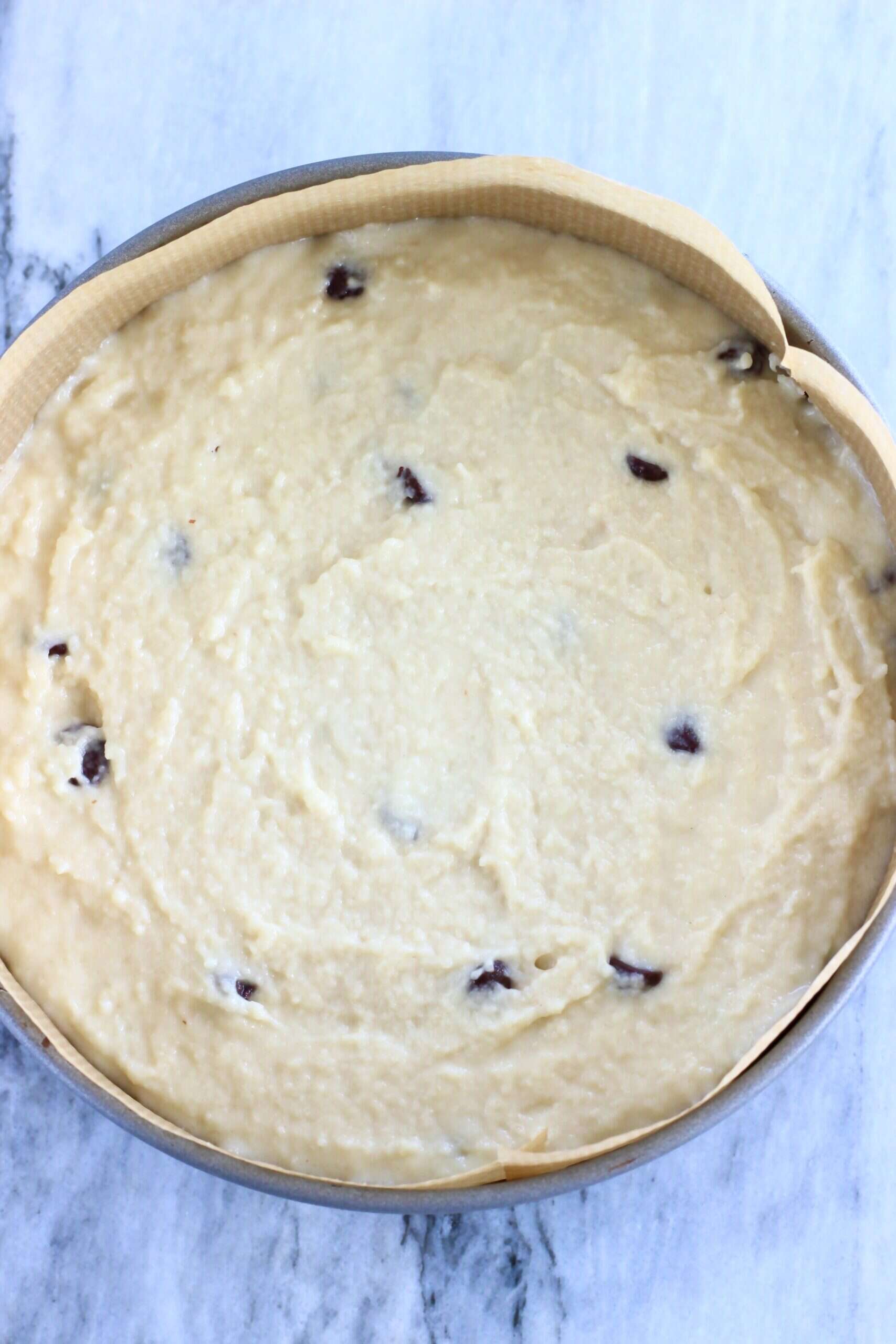 Raw gluten-free vegan chocolate chip cake batter in a round springform baking tin lined with baking paper