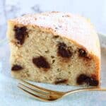 A slice of gluten-free vegan chocolate chip cake on a plate with a fork