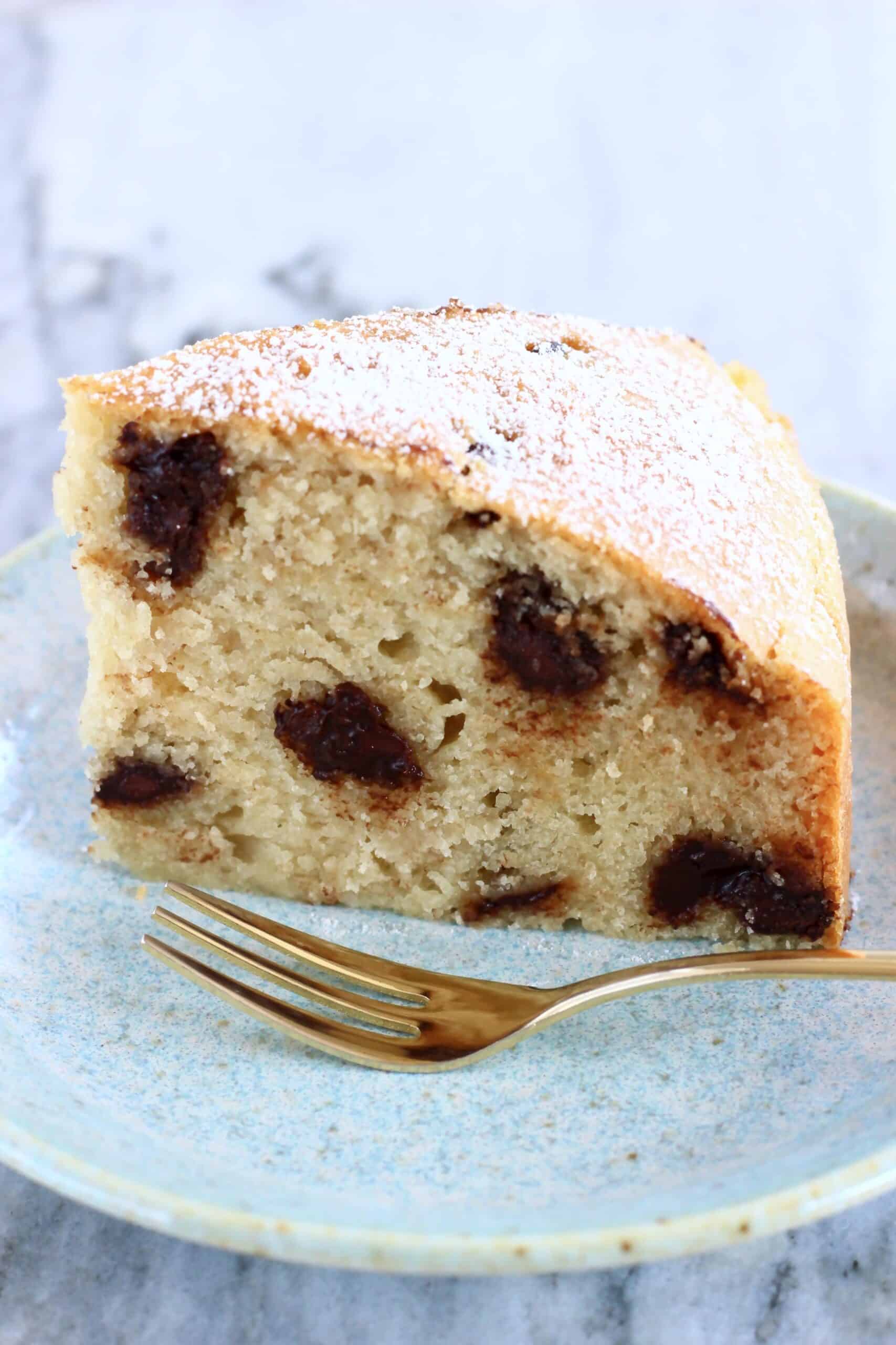 A slice of gluten-free vegan chocolate chip cake on a plate with a fork