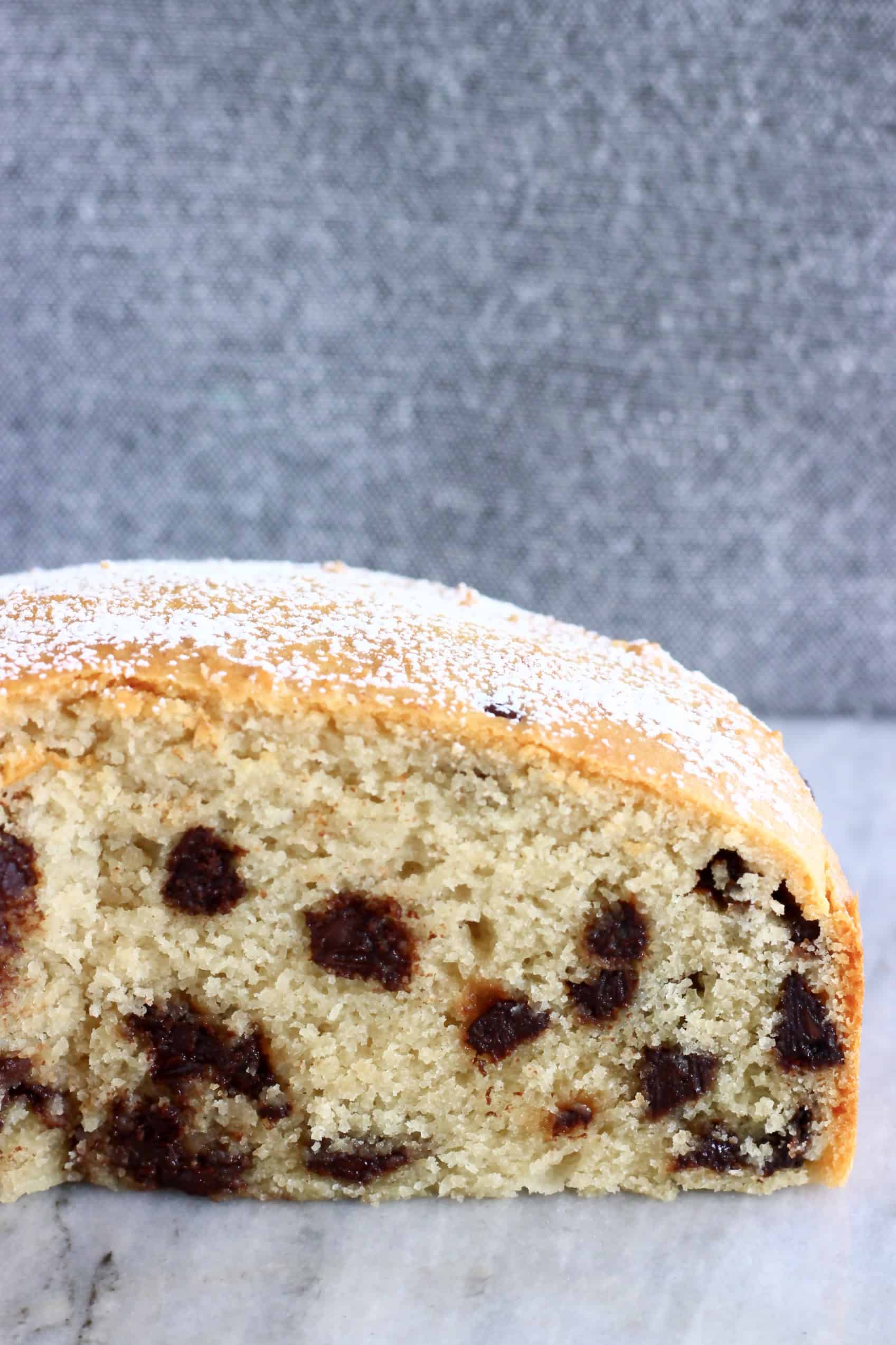 A sliced gluten-free vegan chocolate chip cake against a grey background