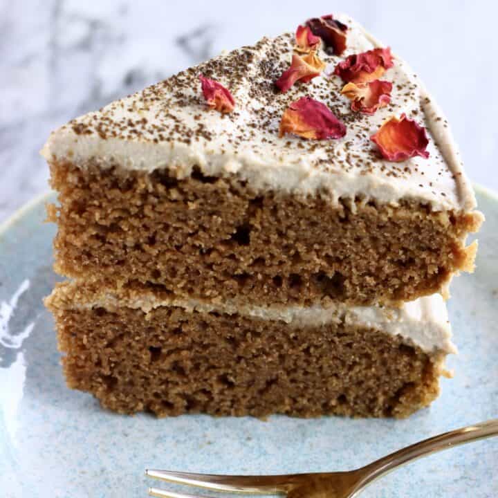A slice of vegan hojicha latte cake topped with rose petals on a plate with a fork