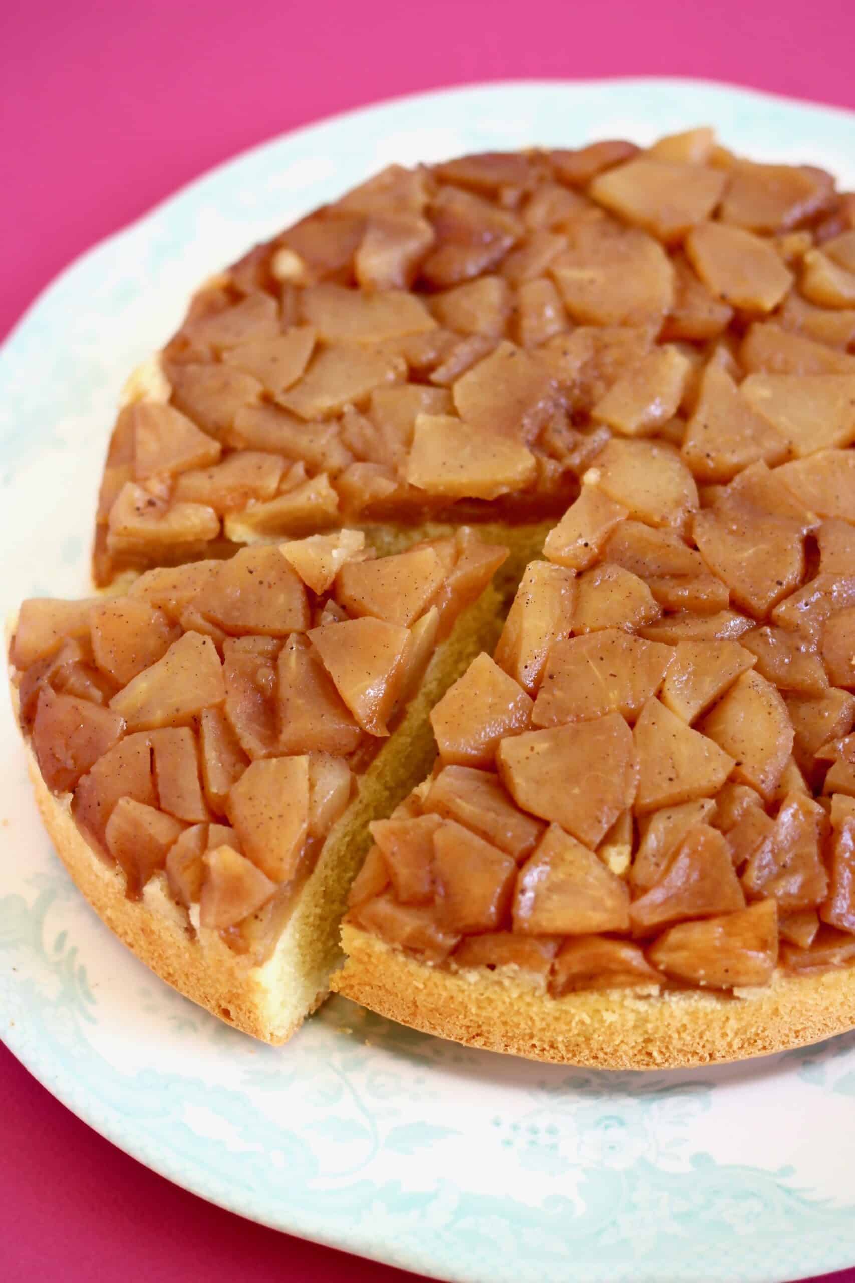 A gluten-free vegan apple upside down cake on a plate with a slice cut out of it
