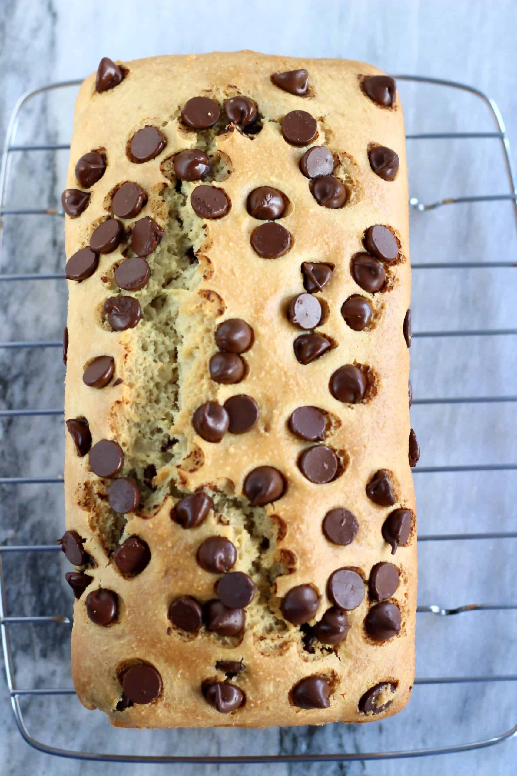 A baked loaf of gluten-free vegan chocolate chip bread on a wire rack