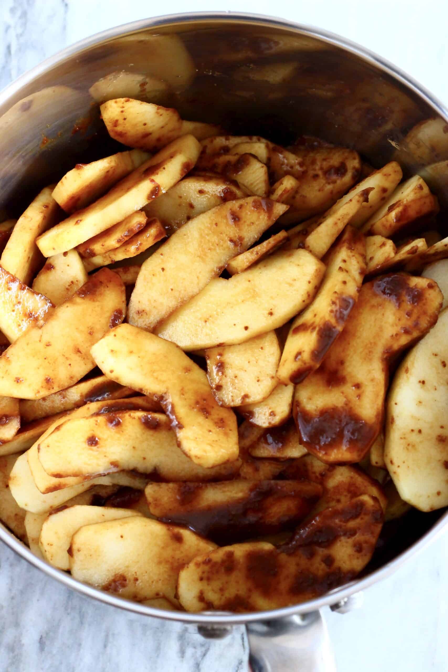 Sliced raw apples with coconut sugar and cinnamon in a saucepan