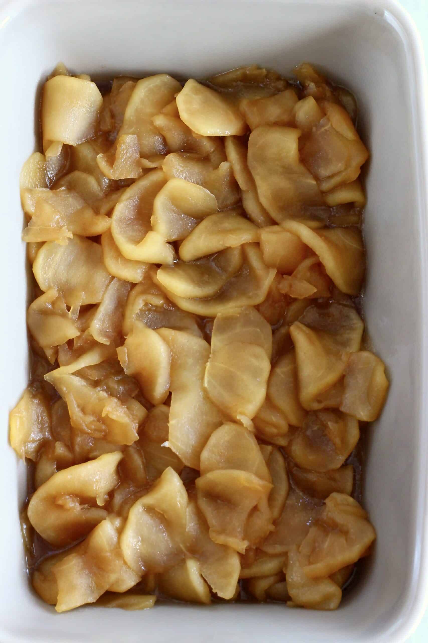 Cooked sliced apples with coconut sugar in a rectangular baking dish
