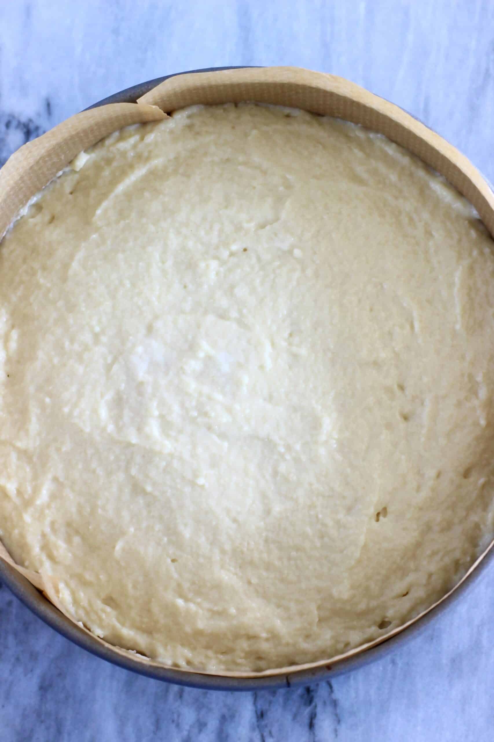 Raw vegan lemon olive oil yogurt cake batter in a round springform baking tin lined with baking paper