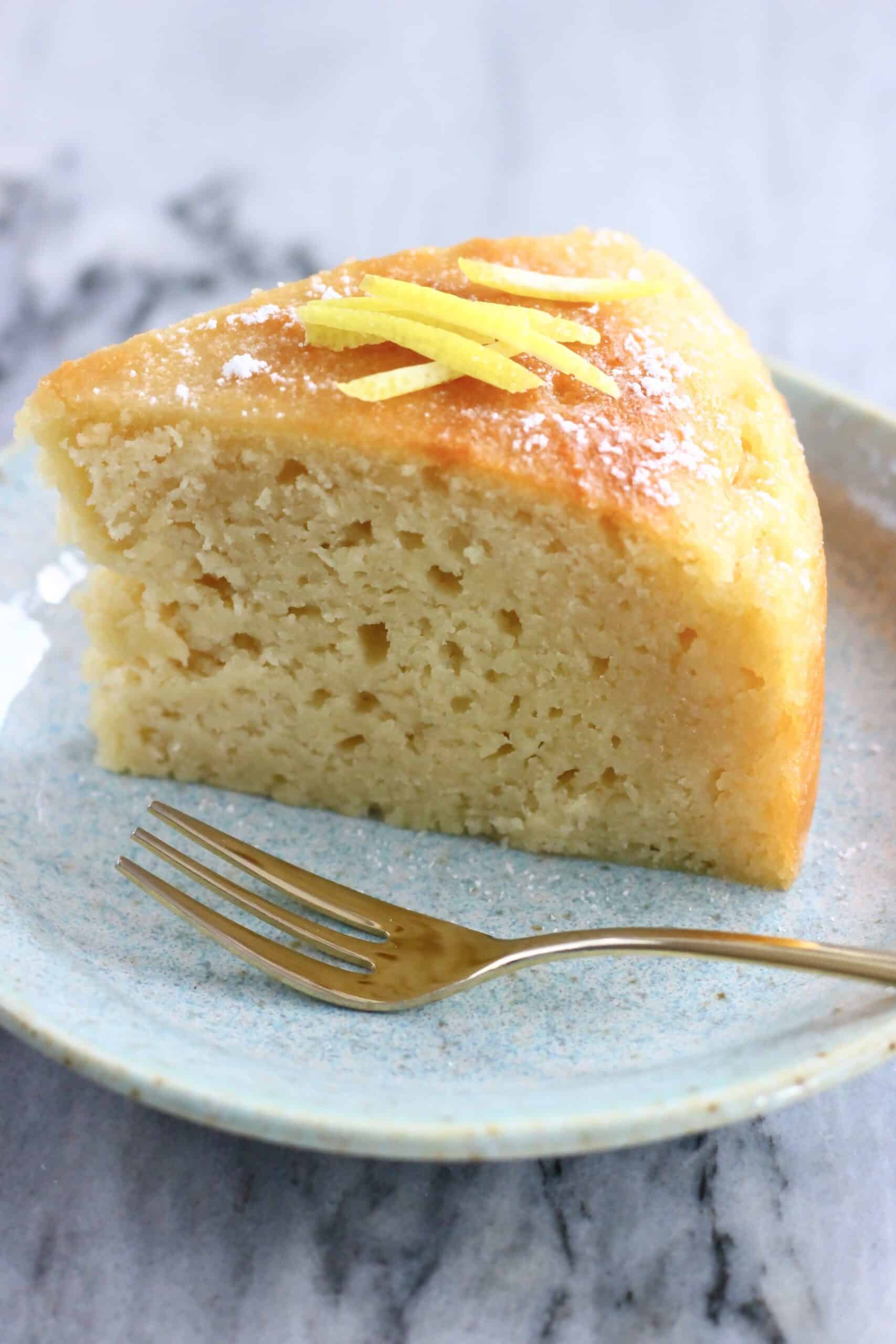 A slice of vegan lemon olive oil yogurt cake on a plate with a fork