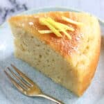 A slice of vegan lemon olive oil yogurt cake on a plate with a fork