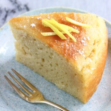 A slice of vegan lemon olive oil yogurt cake on a plate with a fork