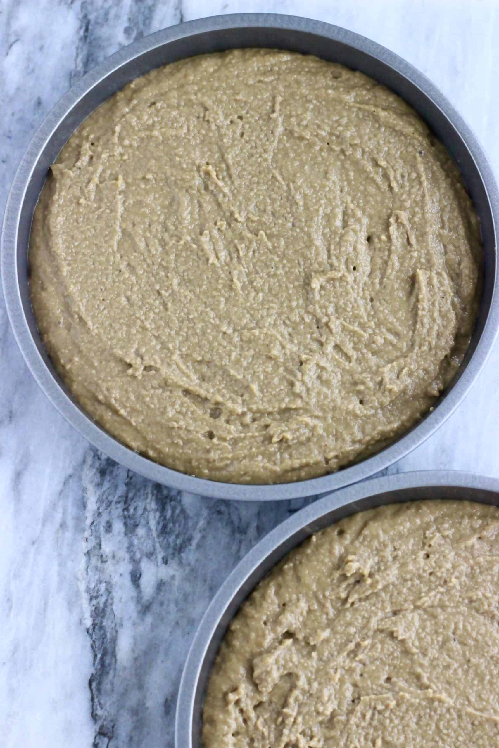 Raw vegan hojicha latte cake batter in two round baking tins