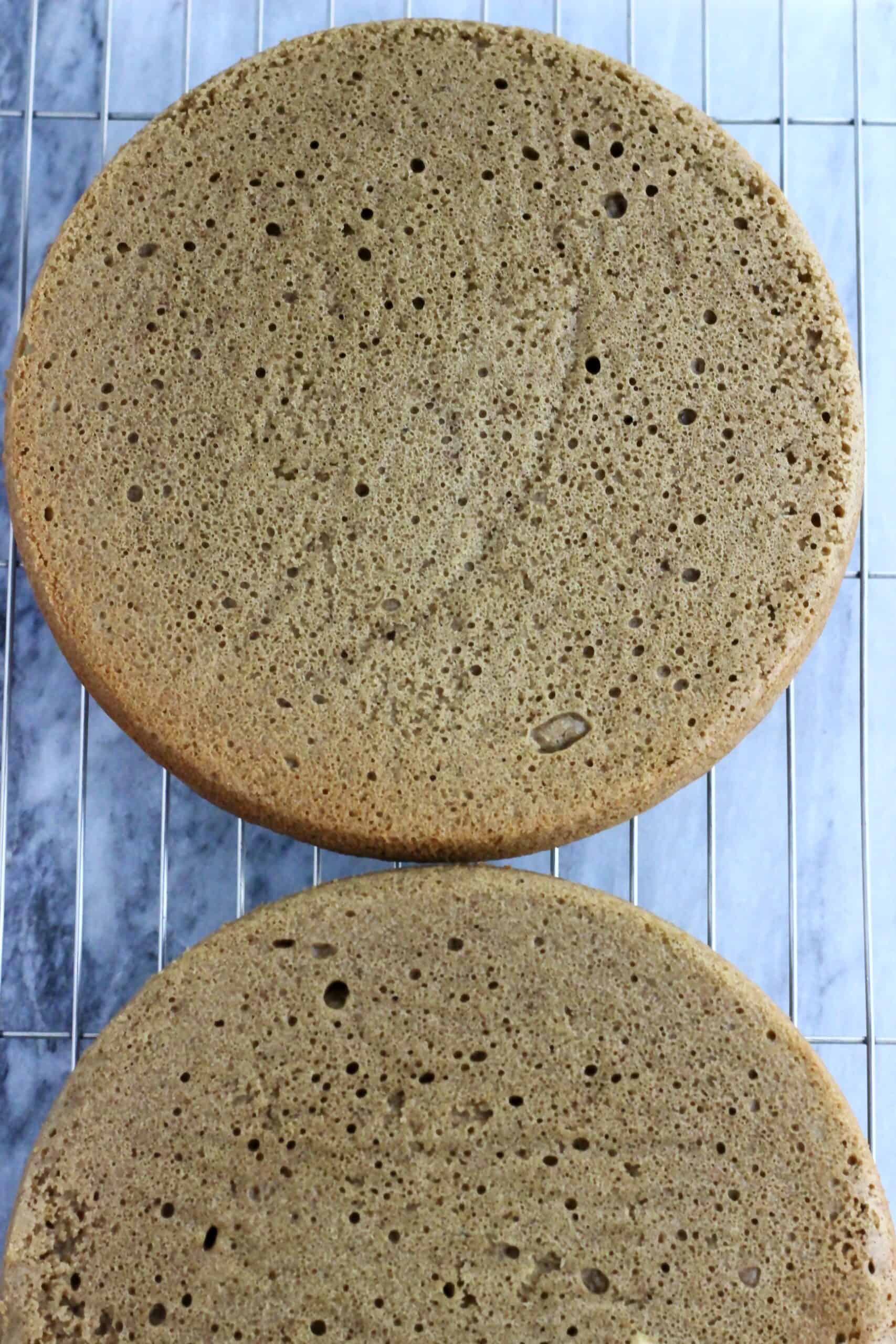 Two baked vegan hojicha latte cake sponges on a wire rack