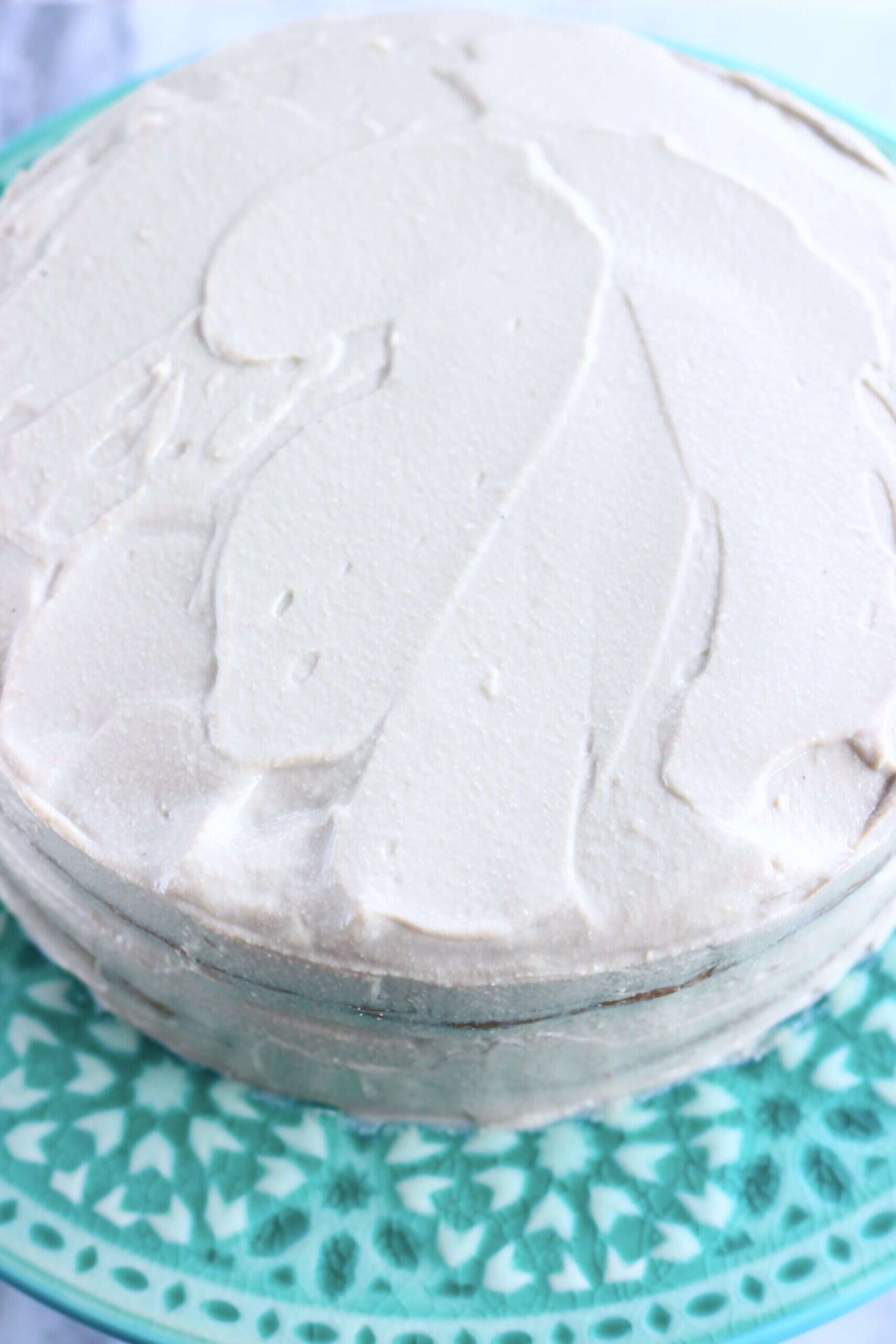 A vegan hojicha latte cake covered in frosting on a cake stand
