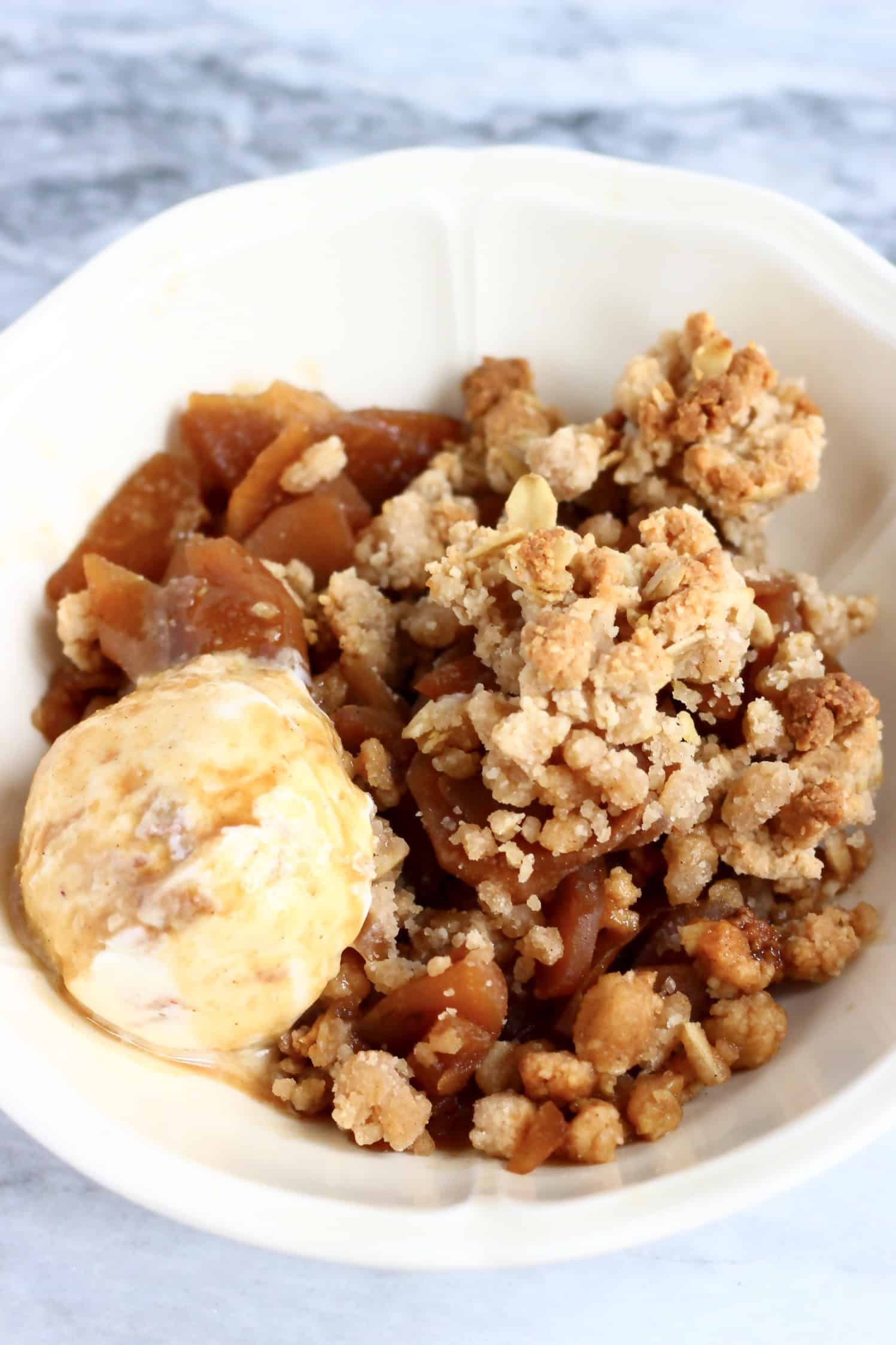 Gluten-free vegan apple crumble with a scoop of ice cream in a bowl