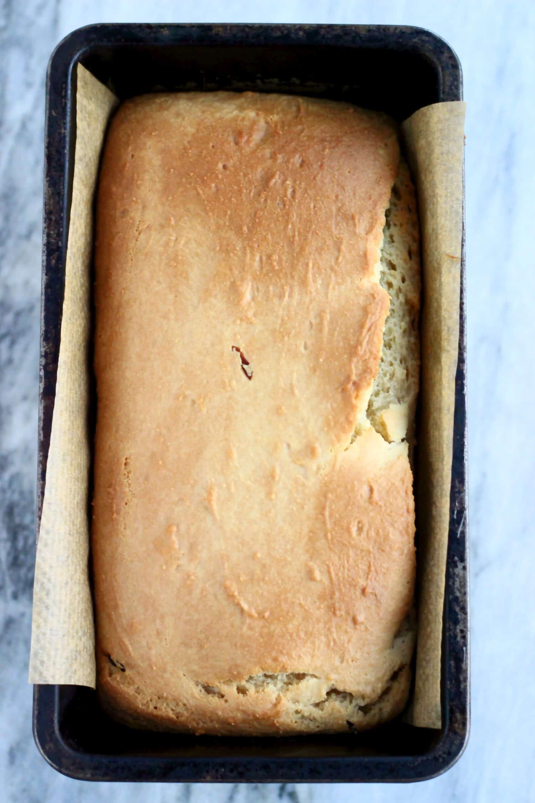 A loaf of gluten-free bread yogurt loaf cake in a loaf tin lined with baking paper