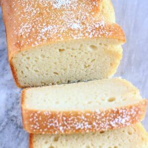 A loaf of gluten-free vegan yogurt loaf cake with two slices next to it