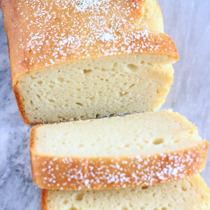 A loaf of gluten-free vegan yogurt loaf cake with two slices next to it