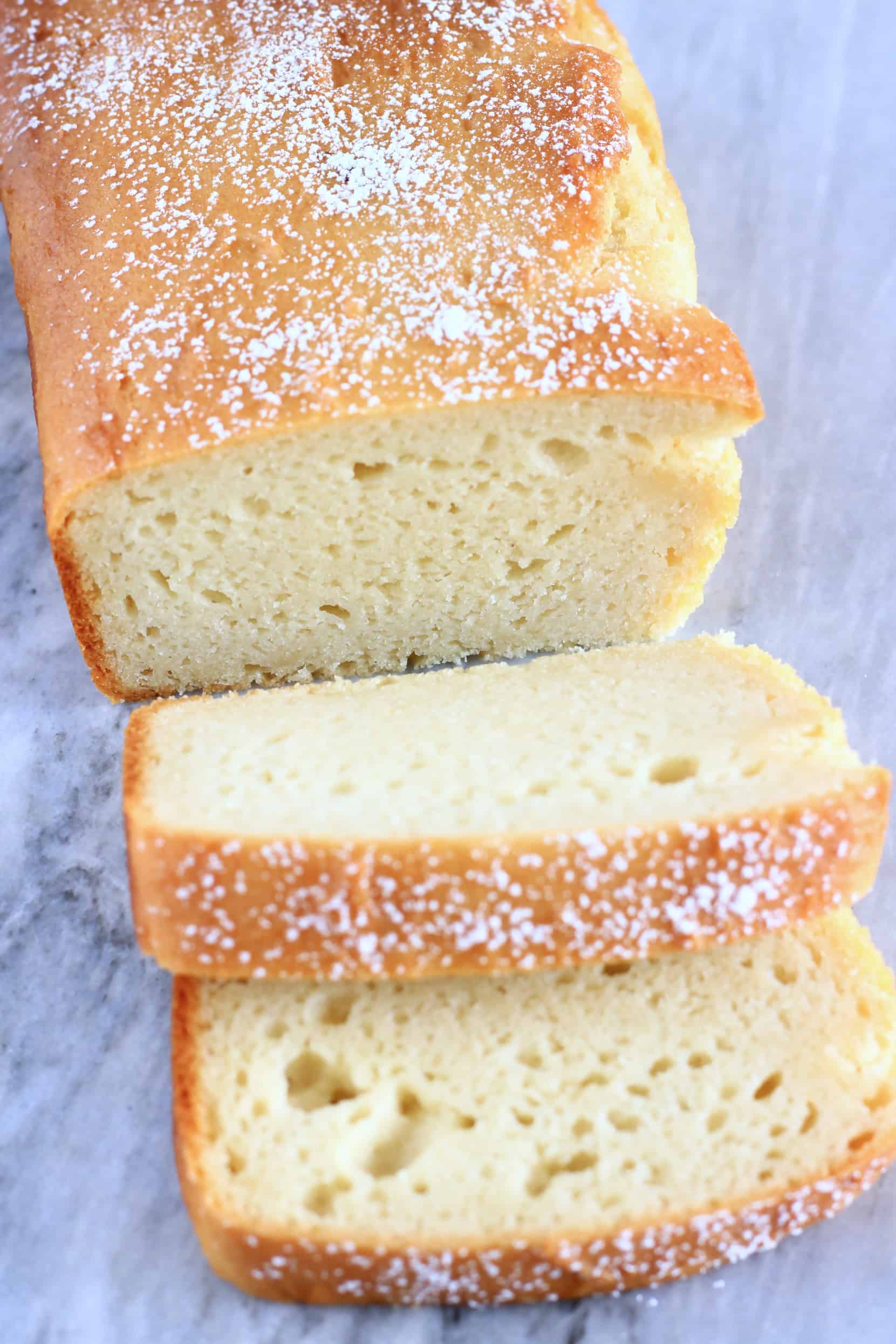 A loaf of gluten-free vegan yogurt loaf cake with two slices next to it