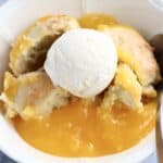 A portion of vegan lemon cobbler with vanilla ice cream in a bowl with a spoon