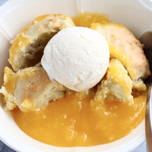 A portion of vegan lemon cobbler with vanilla ice cream in a bowl with a spoon